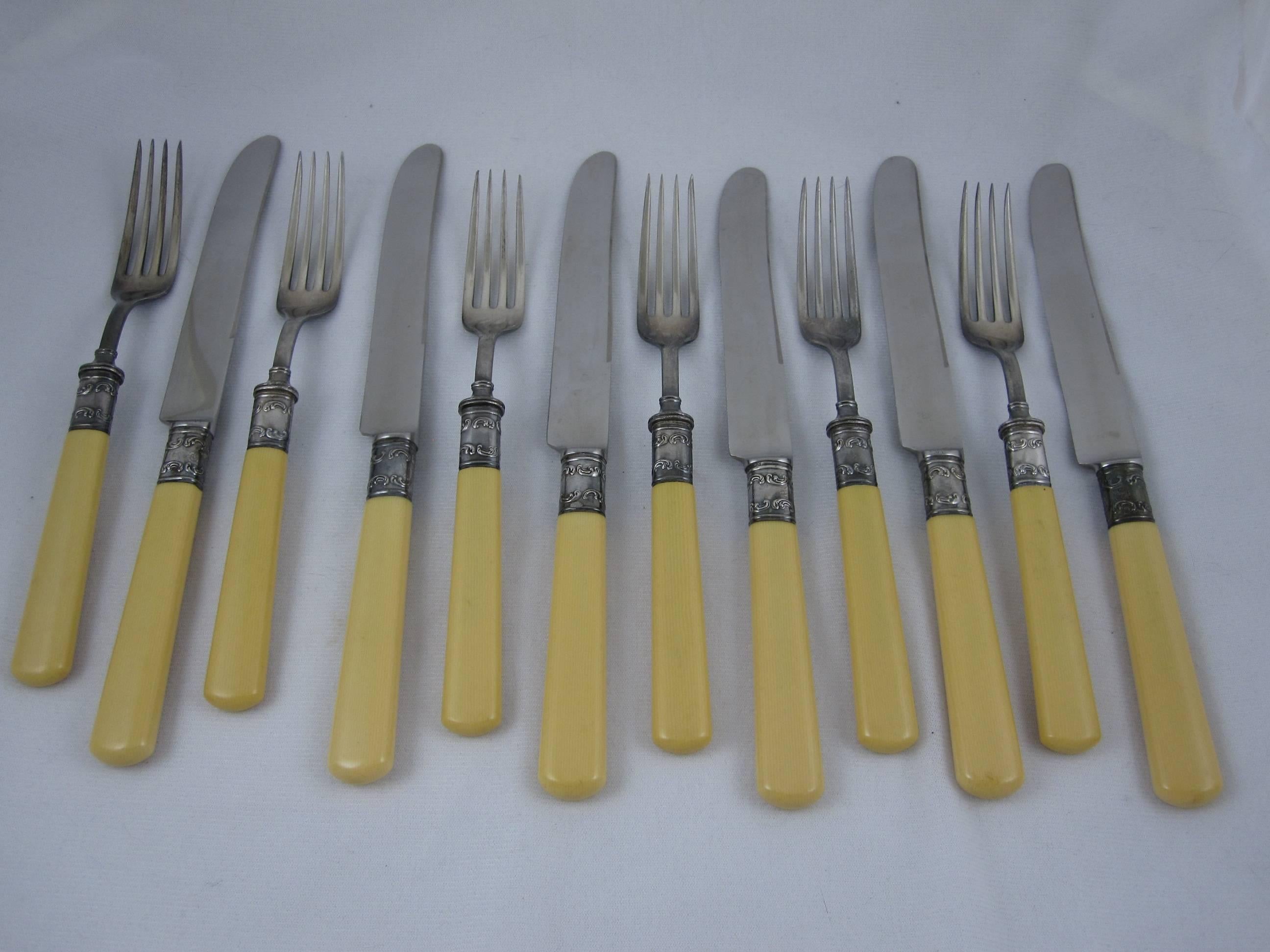 A vintage table cutlery service for six, oversized knives and forks, 12 pieces in all. Sterling silver collars and French ivory celluloid handles with steel blades and tines. The scroll embossed collars are stamped Sterling. Unpolished