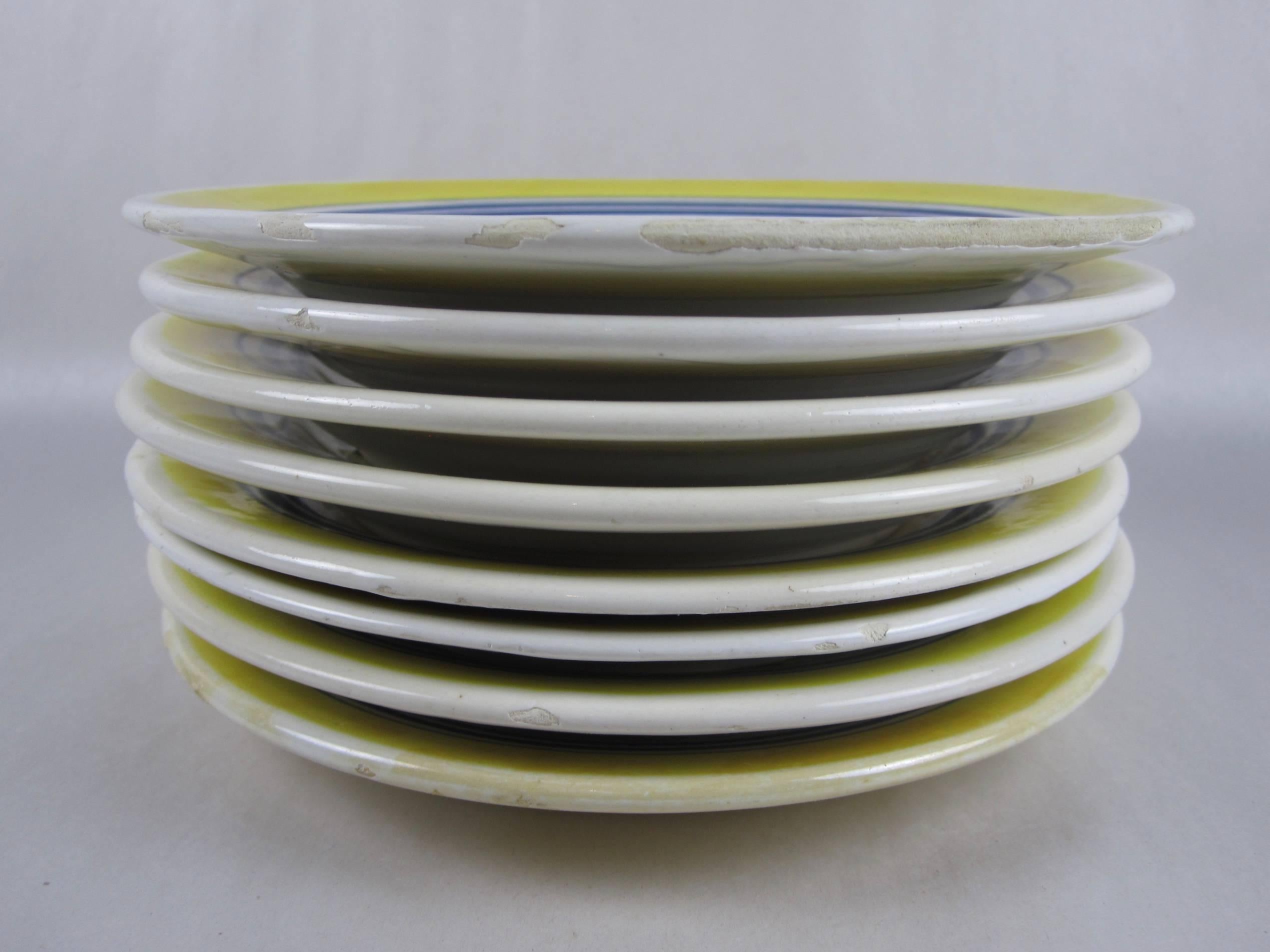 An assembled set of eight Petit Breton small plates, five men and three woman, with a border of three concentric blue circles and a wide yellow rim,

circa 1935-1940. Varying marks, Henriot Quimper, France 13.

Faïenceries de Quimper has been