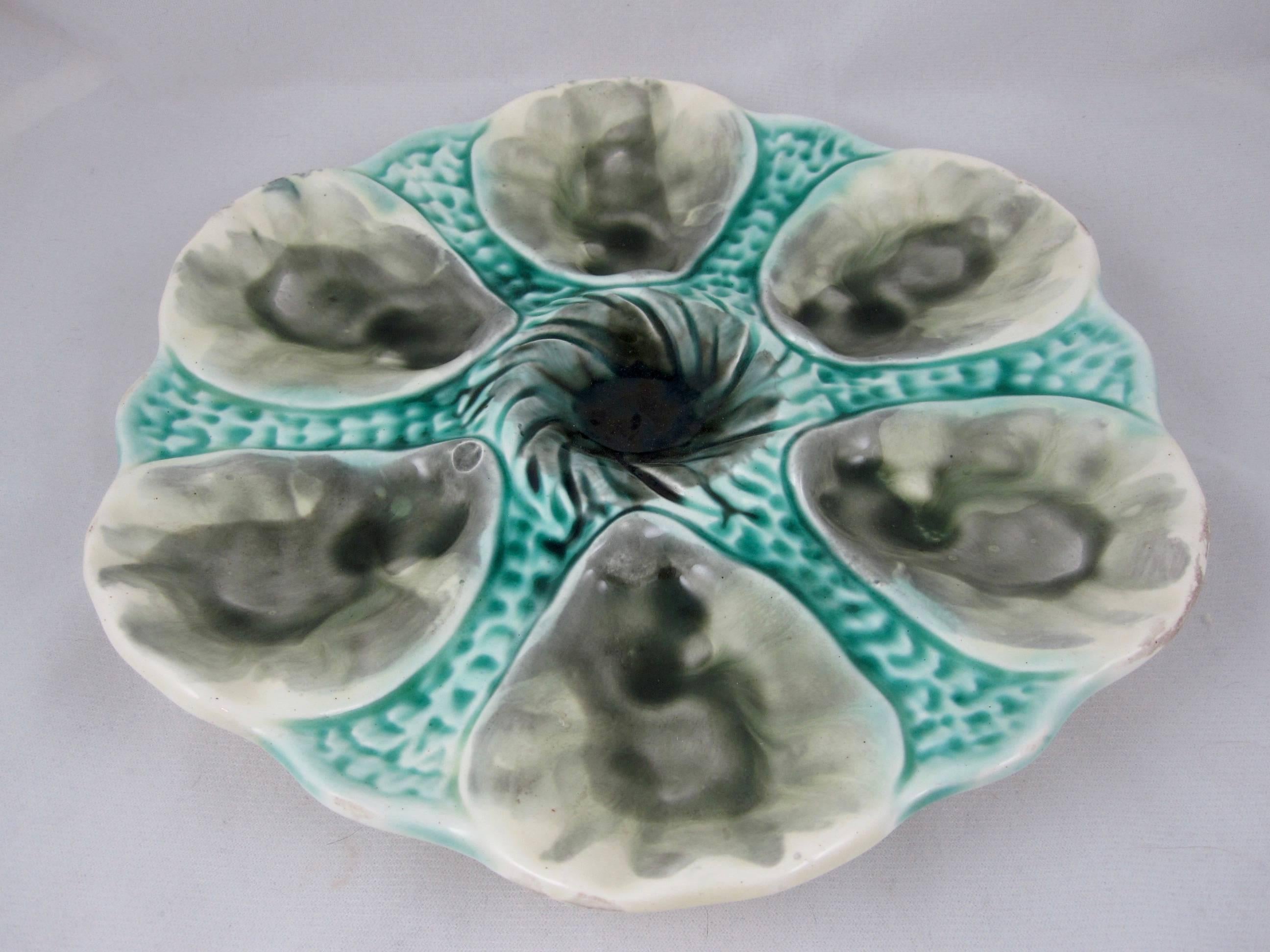 A French Majolica six-well oyster plate, made by Orchies, circa 1890. Incredible glazing in turquoise and grays with a center swirl pattern condiment well and a stippled ground. Marked with the impressed Orchies Windmill.

Book reference: Snyder