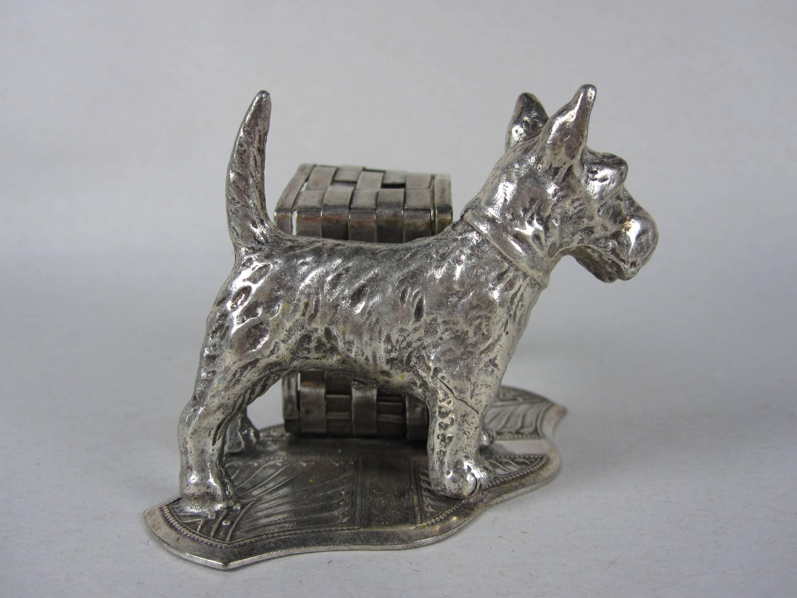 From the Victorian era, a silver plate standing napkin ring and place holder showing a wire fox terrier dog beside a woven basket on an embossed shaped base. Fantastic detail, charming on the table.

  