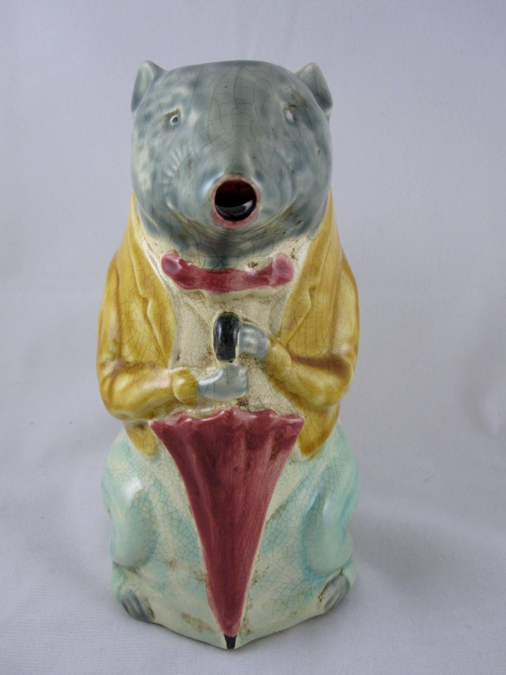 A rare and desirable, late 19th century French Barbotine Majolica, anthropomorphic absinthe pitcher, well known as “The City Badger”.

The animal sits on his haunches, in a mustard yellow waistcoat jacket and red tie, holding a red umbrella in his
