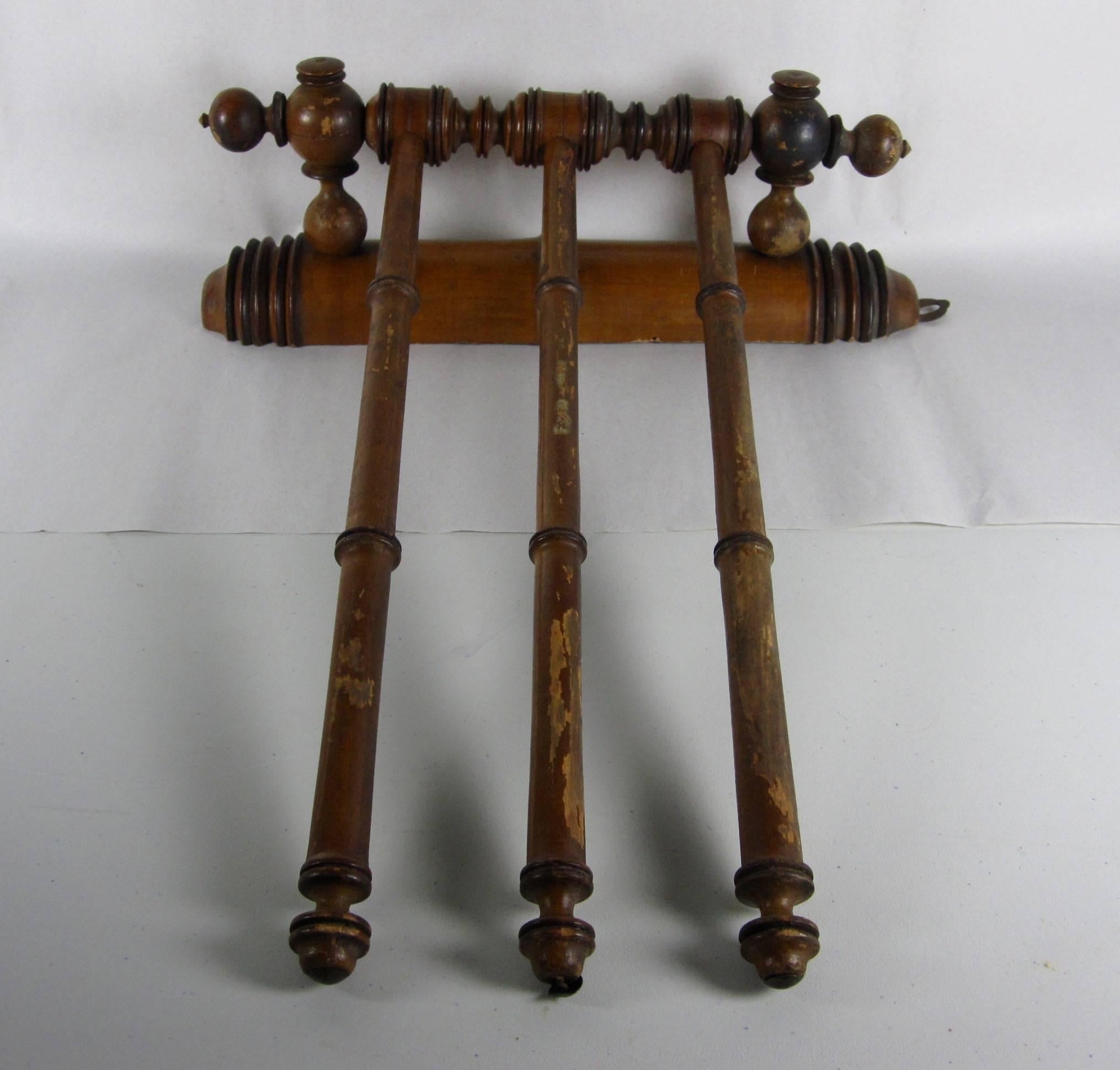 As seen in the cafes, kitchens and baths of France, this perfectly charming antique hand or dish towel wall rack with three swing arms is made of stained fruitwood and made to imitate bamboo. The three tapered arms swing right and left to allow