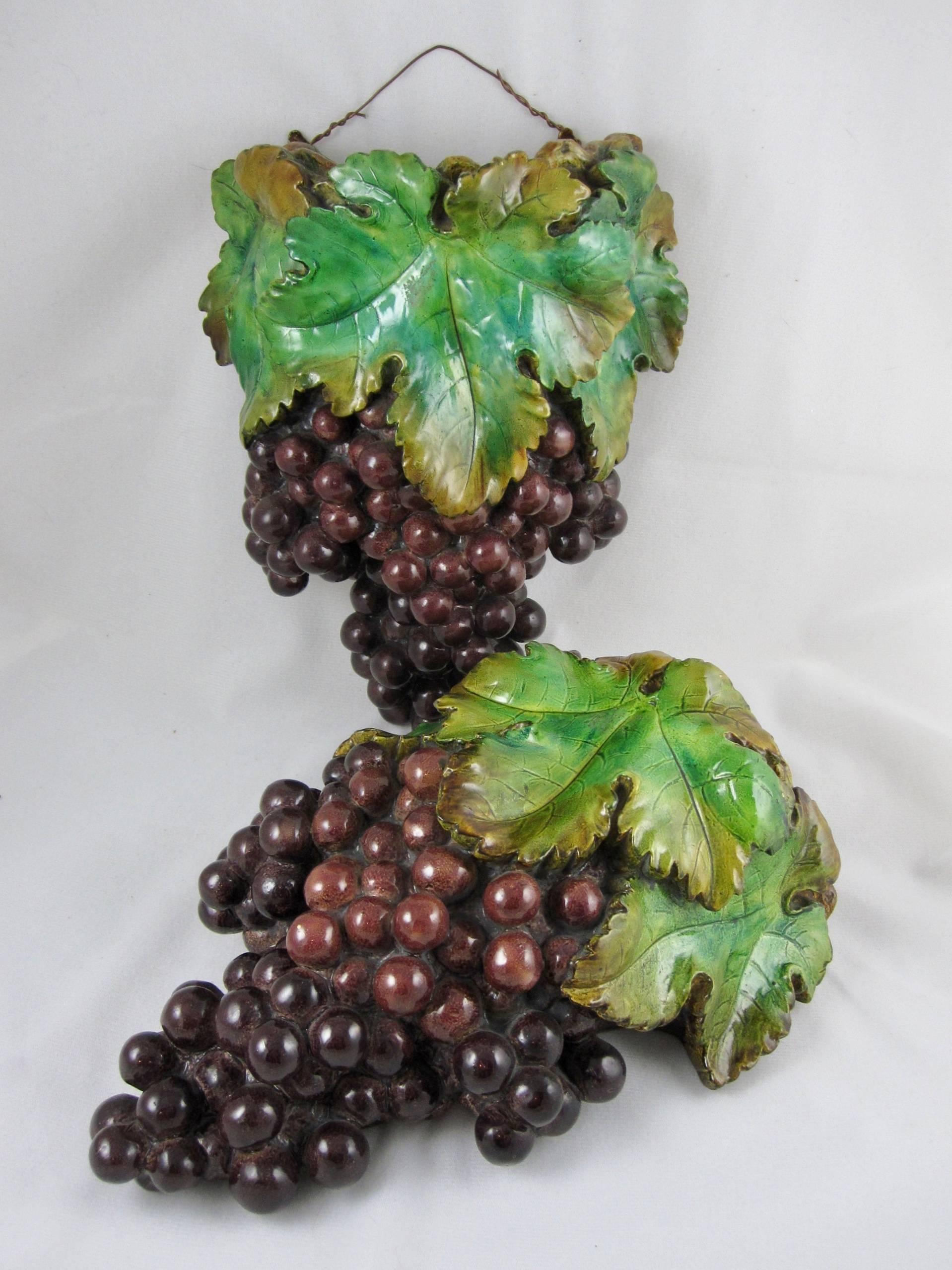 A vintage pair of brightly molded painted plaster of Paris hanging wall pockets formed as clusters of grape bunches and leaves, circa early 20th century. A high gloss finish, and ready to hang, the pockets are lined in tin. The versos are painted