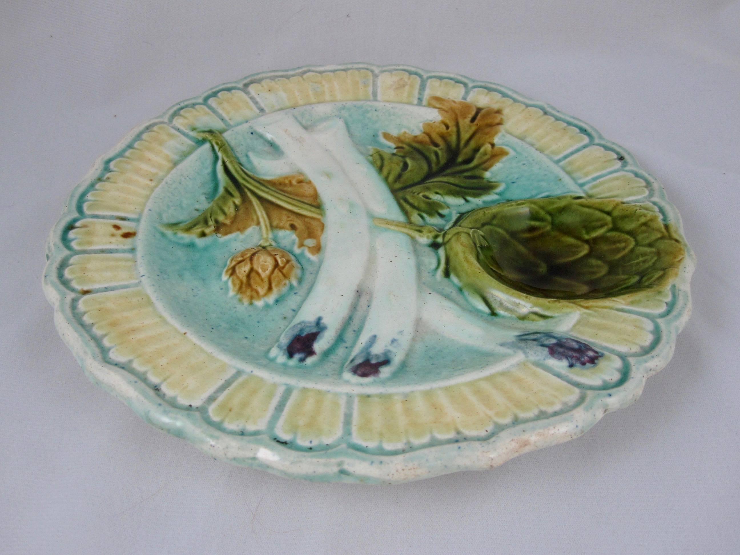 A mid to late 19th century French majolica barbotine asparagus and artichoke plate from the Salins-les-Bains region of Eastern France. Most likely produced in the faïencerie des Capucins. Heavy and thickly potted, showing three asparagus spears and