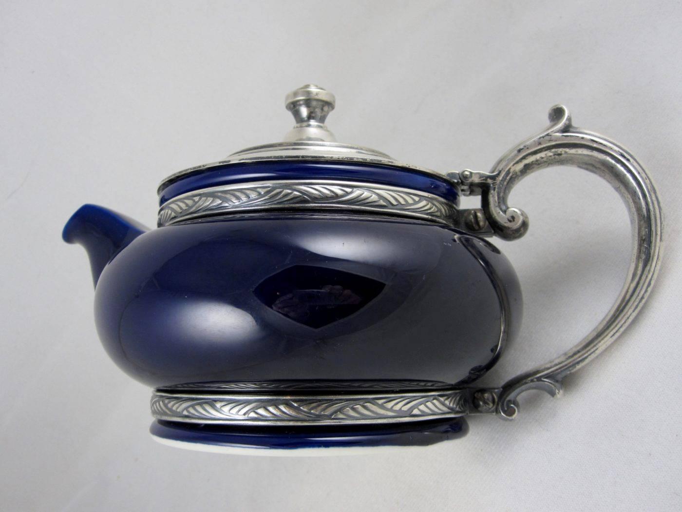 A 1920s hotel teapot, an American collaboration by Lenox and Reed & Barton. Sized to hold two cups of perfectly brewed tea, the cobalt blue ceramic pot is braced in a silver soldered, silver plate holder of a base, handle and a lid with Art Deco
