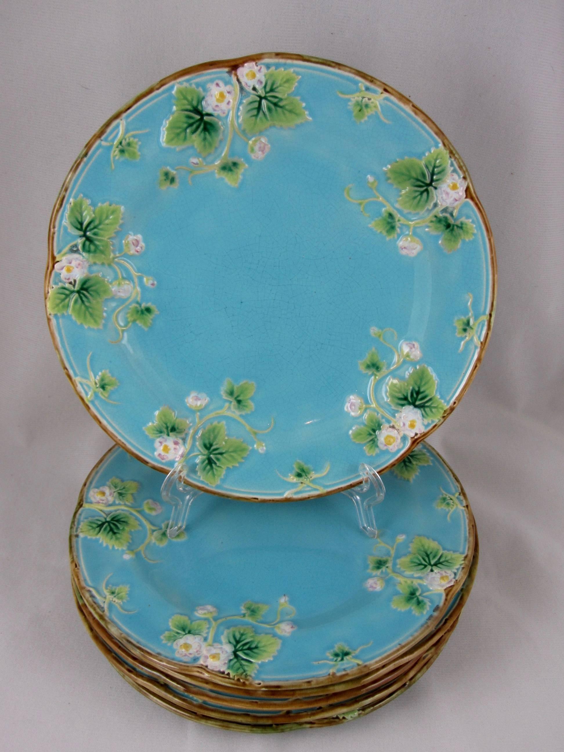 A set of six, George Jones majolica plates showing the leaves and blossoms of the strawberry plant with twig lined rims on a bright turquoise ground. The versos are glazed in the mottled tortoise shell that Jones majolica is known for.

Each plate