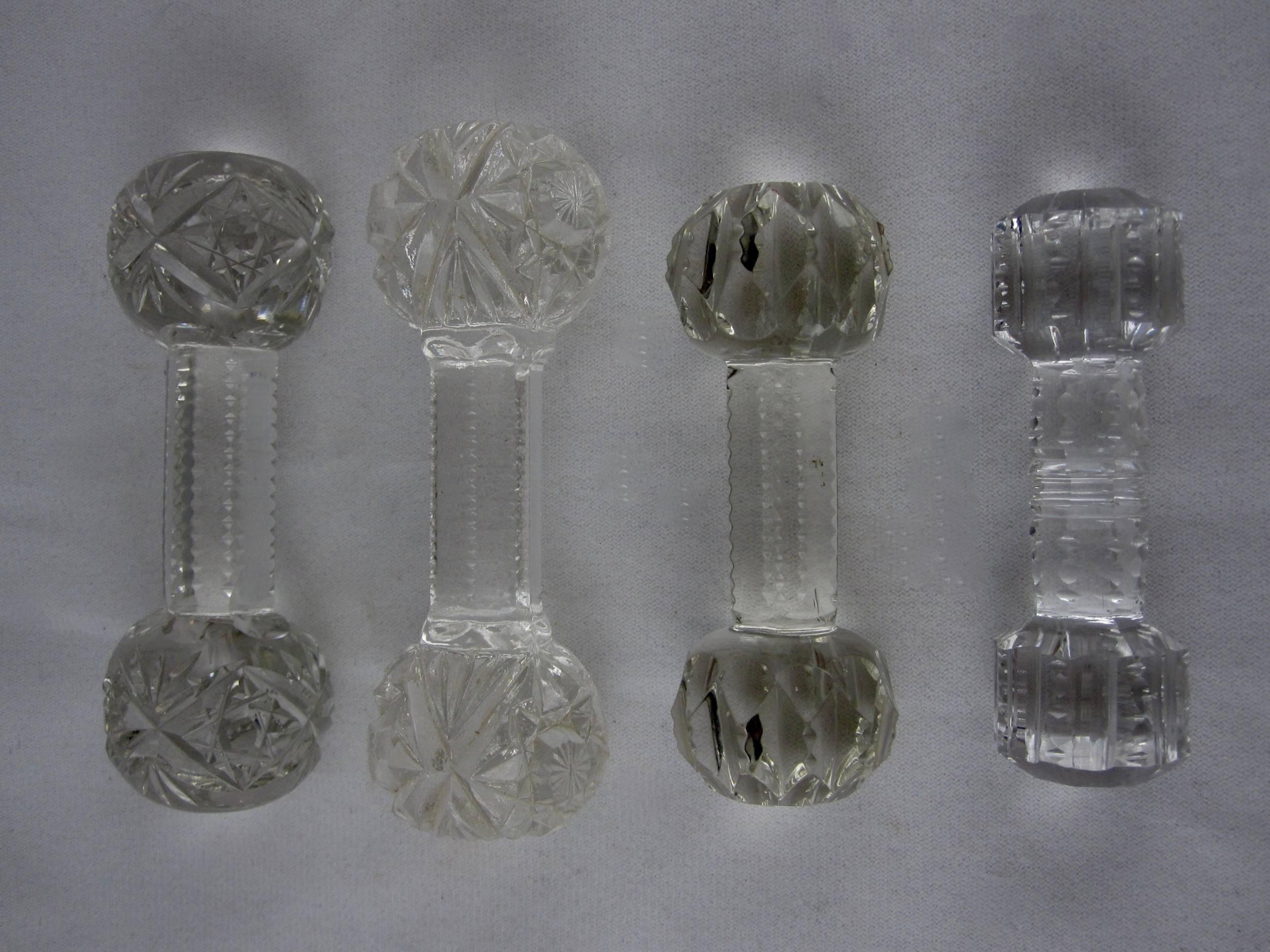 A mixed selection of four cut crystal dumbbell knife rests, mid-late 19th century.

Star-cut end balls with a notched six-sided centre, 4.25 L x 1.5 W x 1.25 H
Fully cut star end balls with a notched six-sided centre, 4.25 L x 1.25 H
Faceted