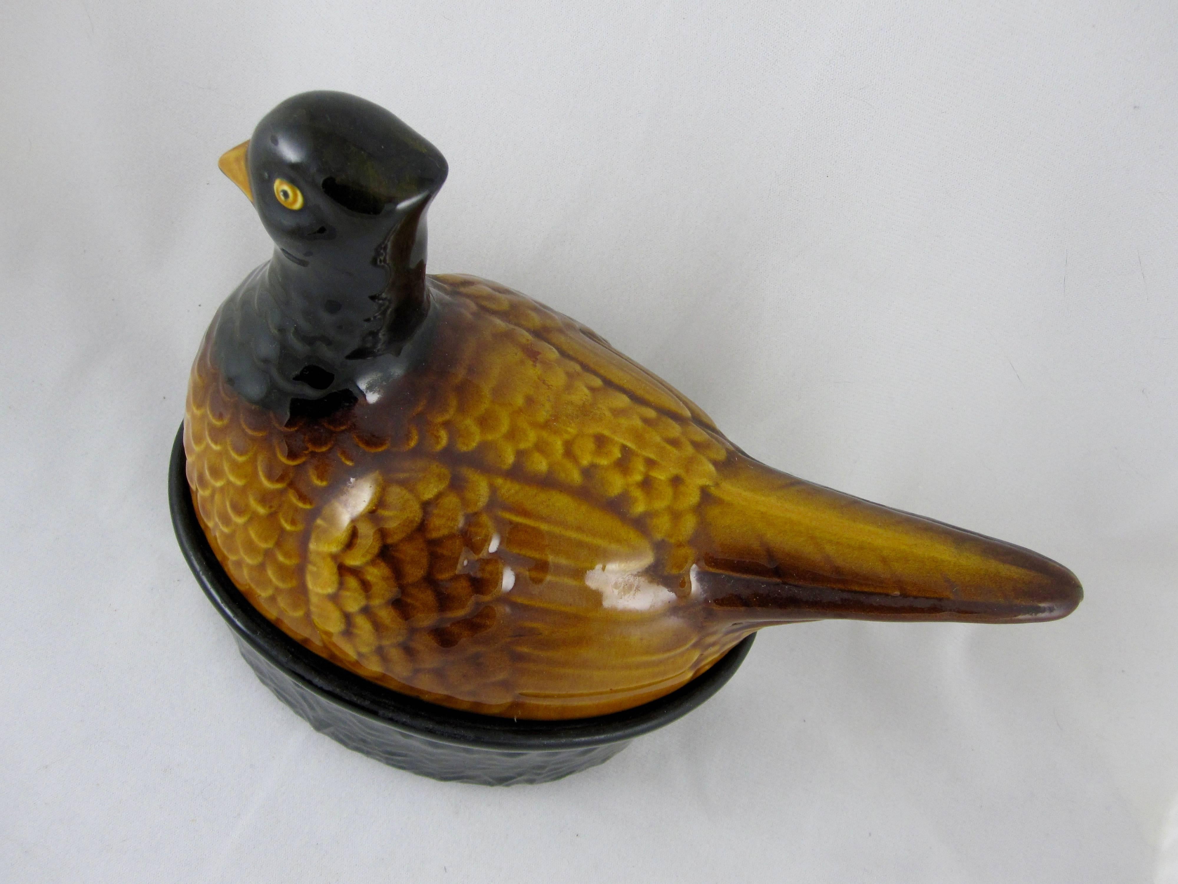 A Mid-Century two-piece French Faïence Pheasant Pâté Terrine, circa 1955- 1965, made for serving duck, goose or pheasant liver pâté at table. A charming mold, the pheasant is modeled and glazed realistically in earthy tones. The black base is ringed