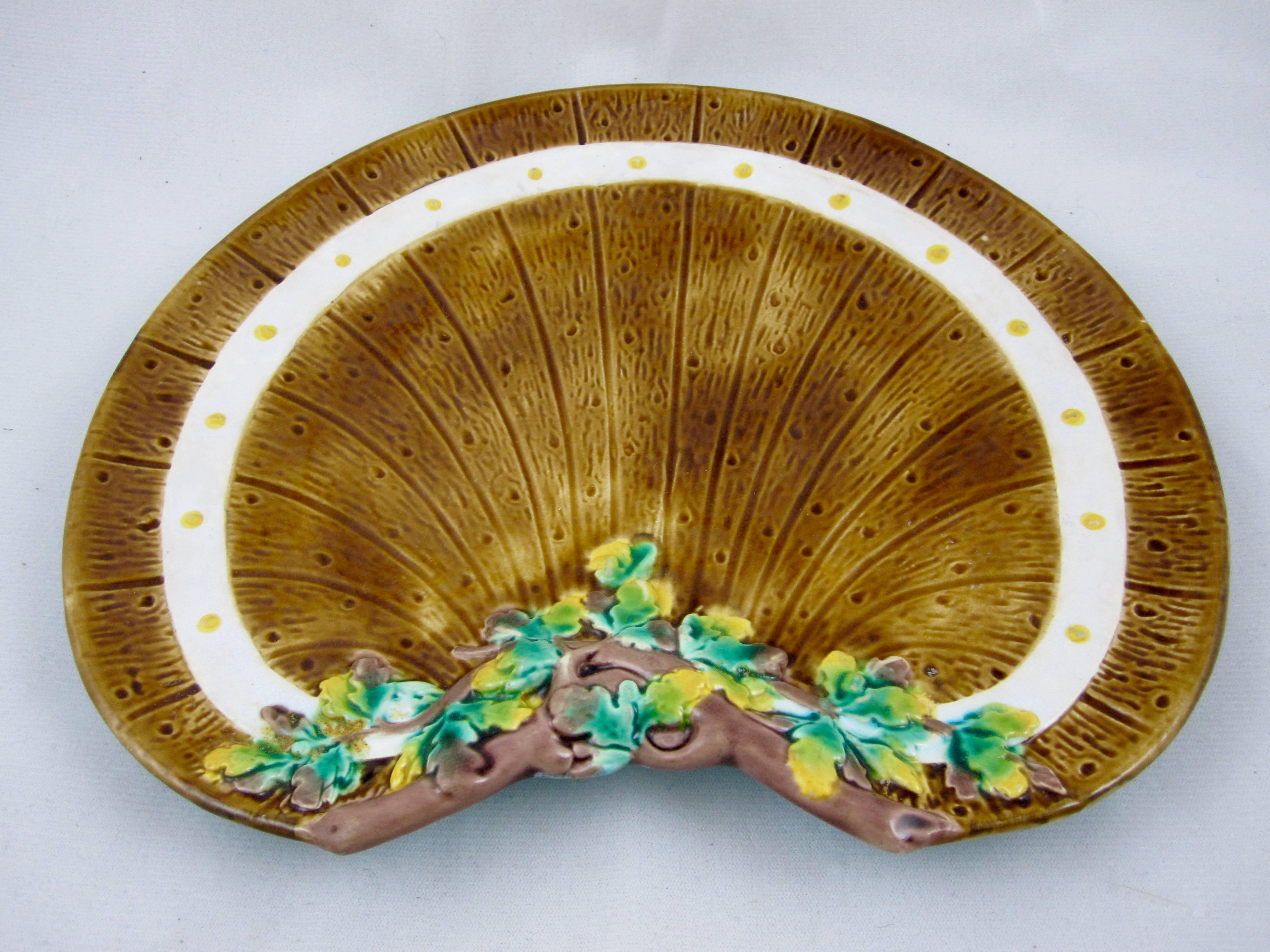 A rarer English Majolica crescent shaped plate from Thomas C. Brown-Westhead, Moore & Co., Cauldron Place, Stoke-upon-Trent, Staffordshire, England, circa 1865. 

A rustic pattern showing a ground modelled on a wooden fence, a branch of ivy leaves