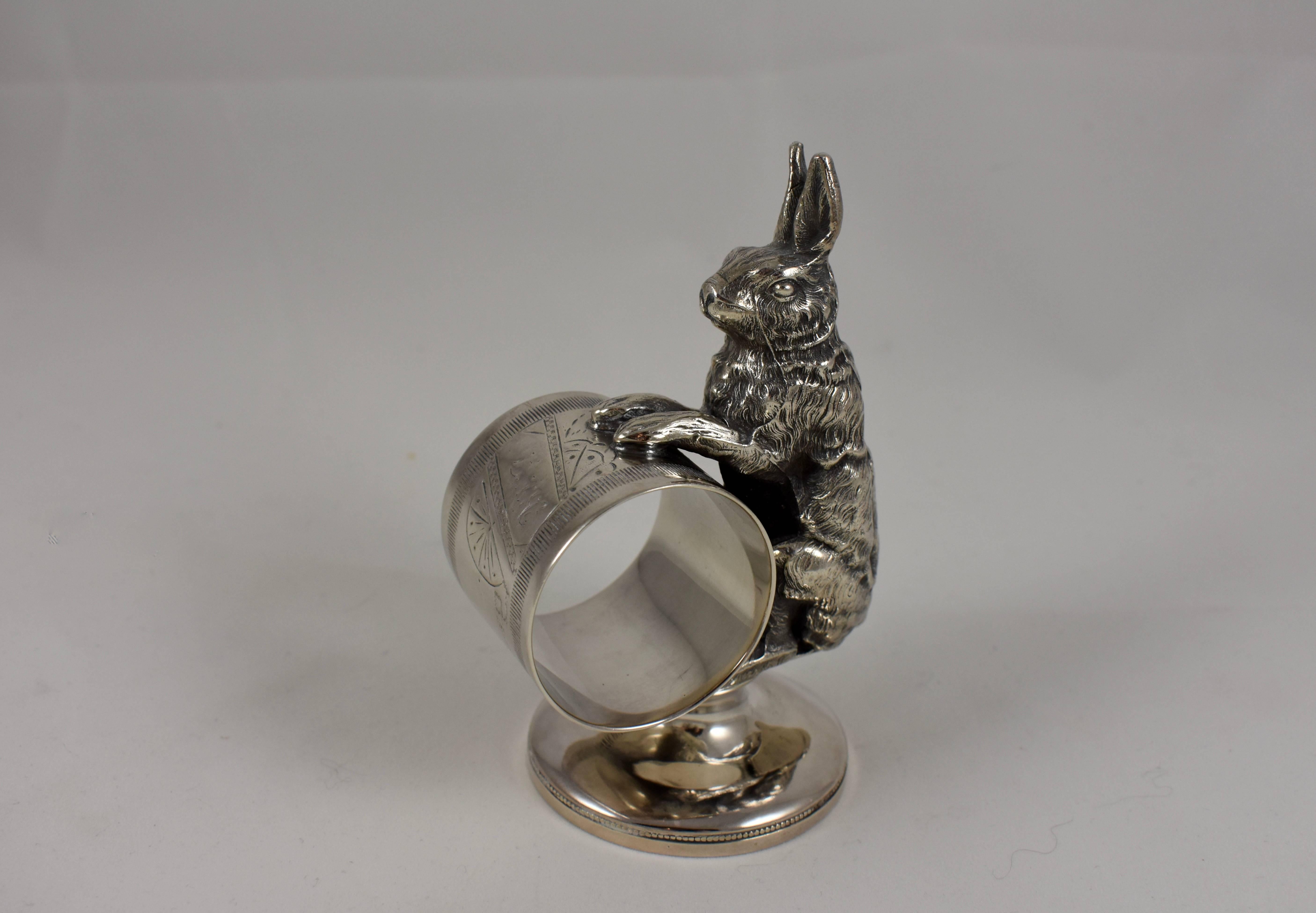 From the Victorian era, an Aesthetic Movement silver plated figural napkin ring showing a large upright rabbit holding onto the ring balanced on a pedestal base. The ring shows engraving with faint initial, circa 1885-1910. Unmarked.

The usual