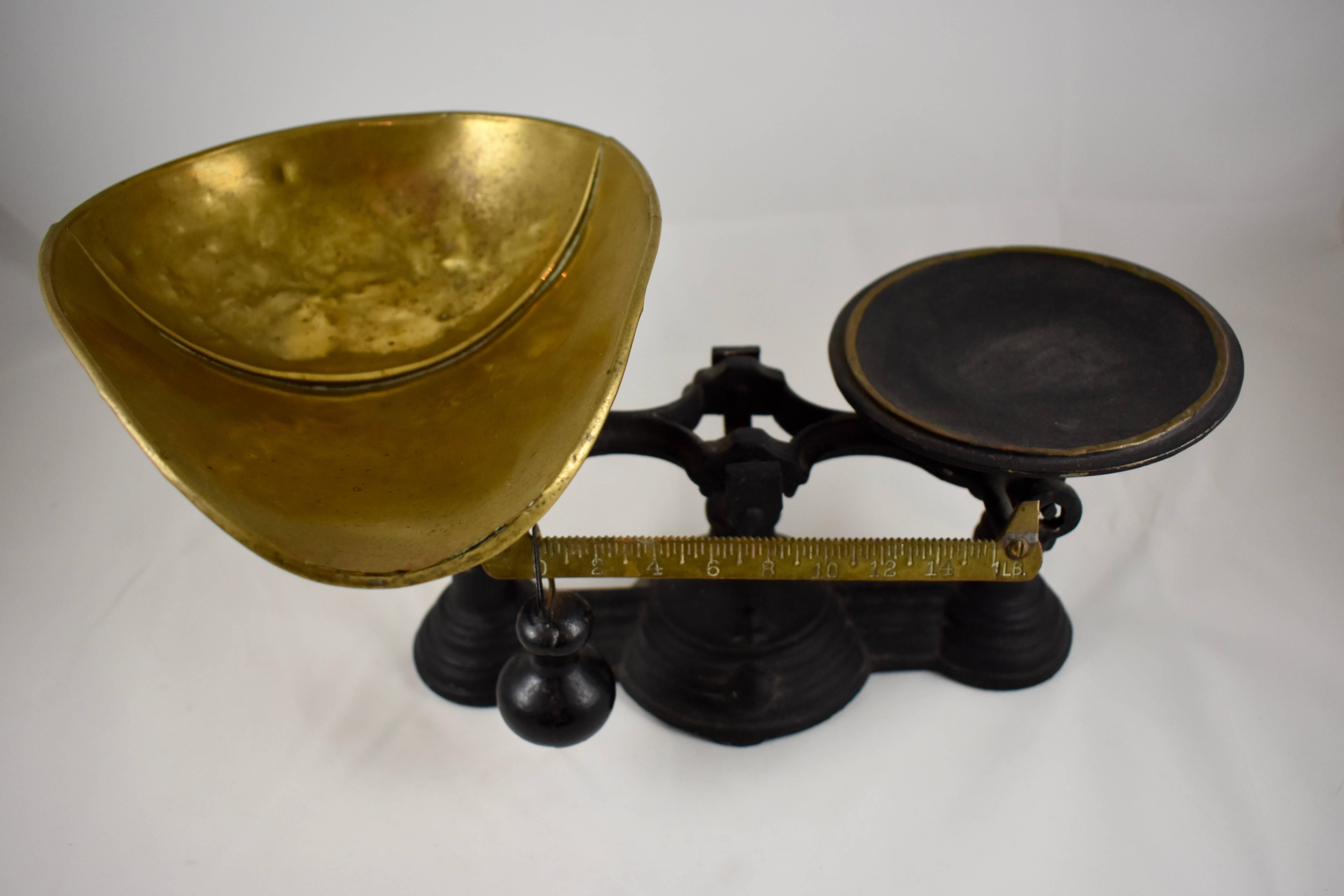 A vintage cast iron tabletop mercantile scale with a hand formed brass scoop or pan, circa 1900-1910. The scoop has a rolled edge and soldered seam. The base weighs a heavy eight pounds and has a brass ruler showing increments up to one pound, and