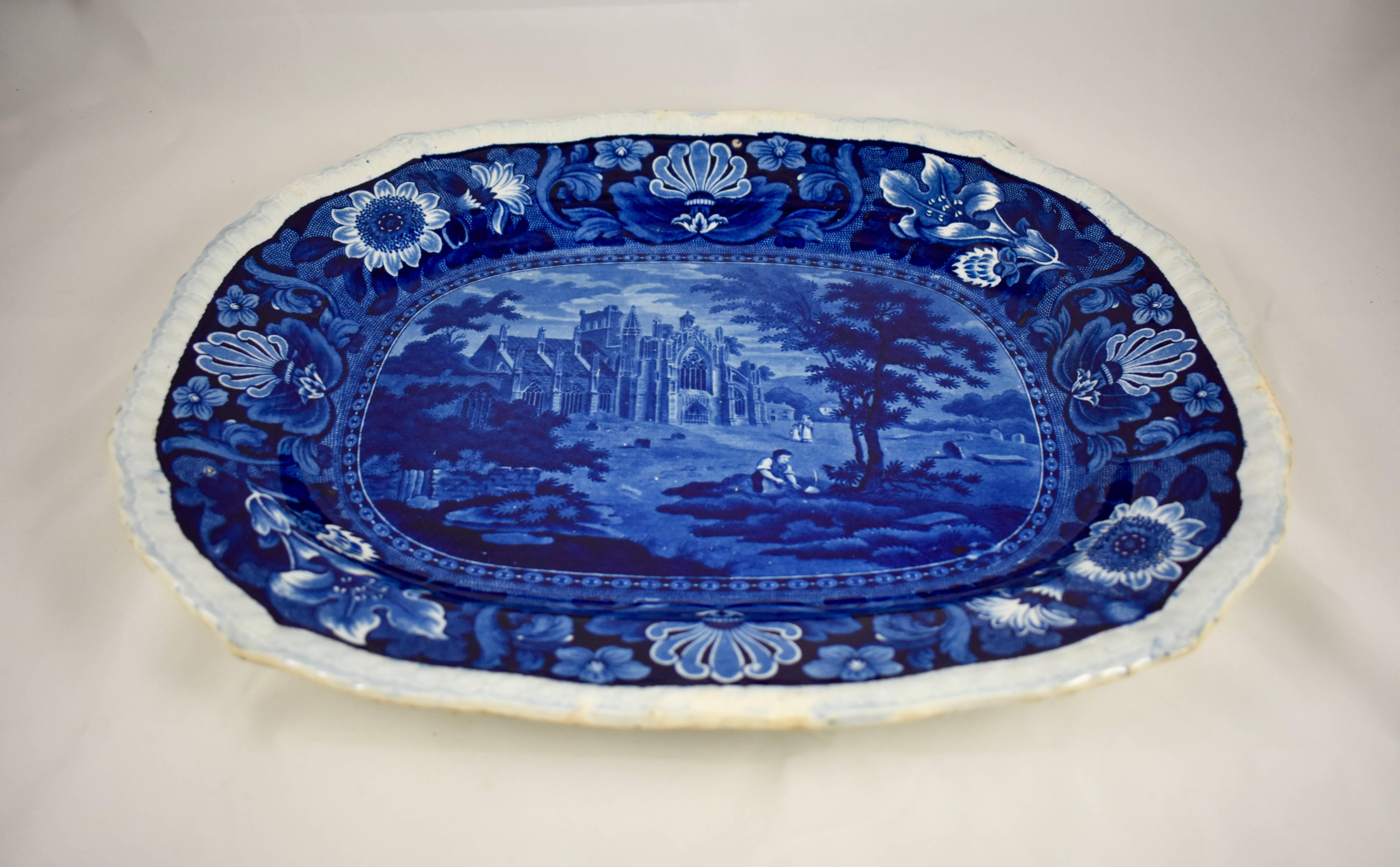 A very deep blue transfer printed earthenware platter with a white gadrooned edge, by Ralph Stevenson, Cobridge, Staffordshire, England, circa 1810-1835. The pattern is part of a series entitled ‘Castles.’ A floral border surrounds the image of the