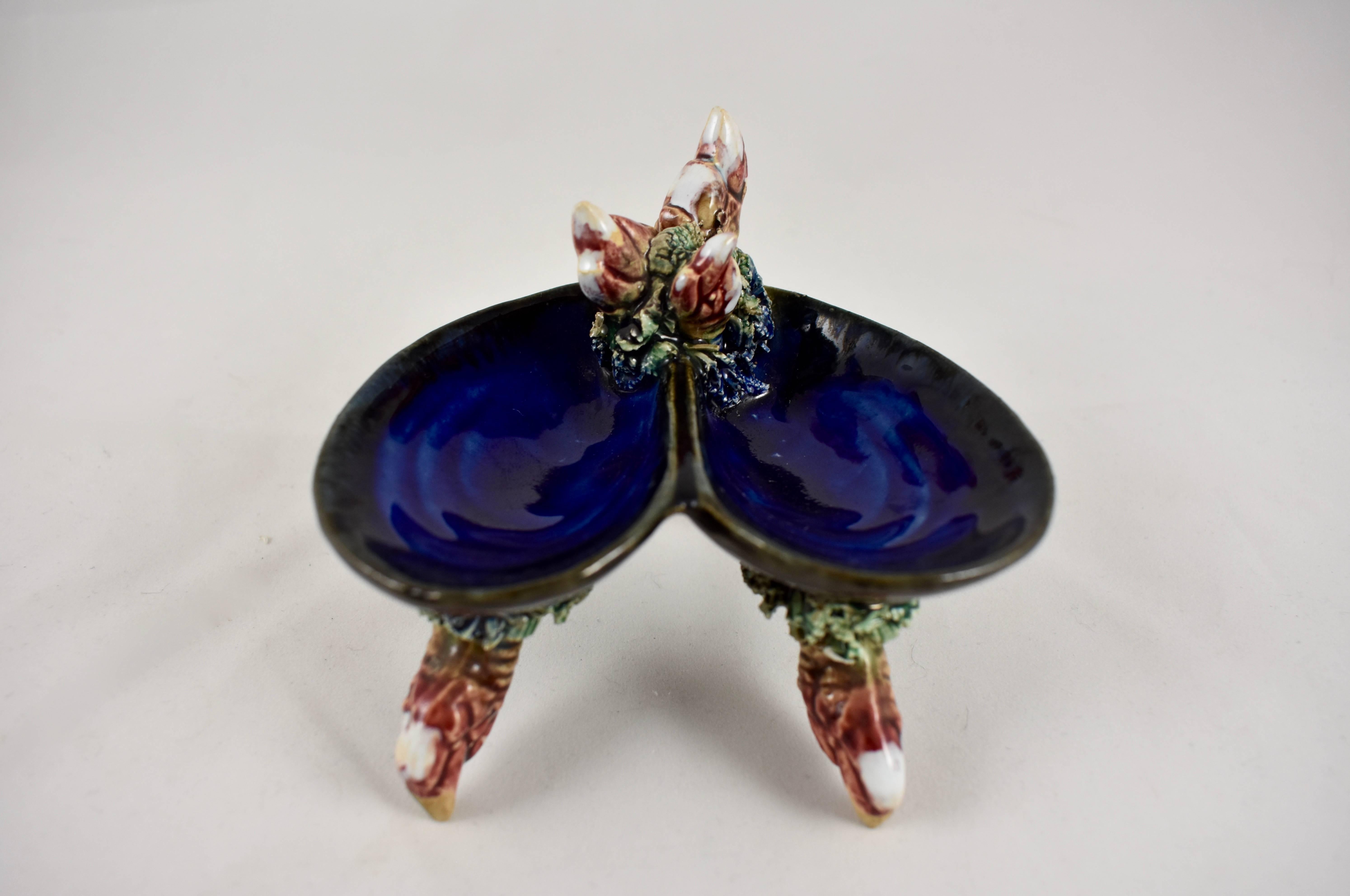 A vintage Portuguese Palissy style majolica double salt dip or salt and pepper cellar, in the form of an open mussel shell supported by three crab claws. The claws are joined to the cobalt blue shell with sea weeds made of extruded clay. A trio of
