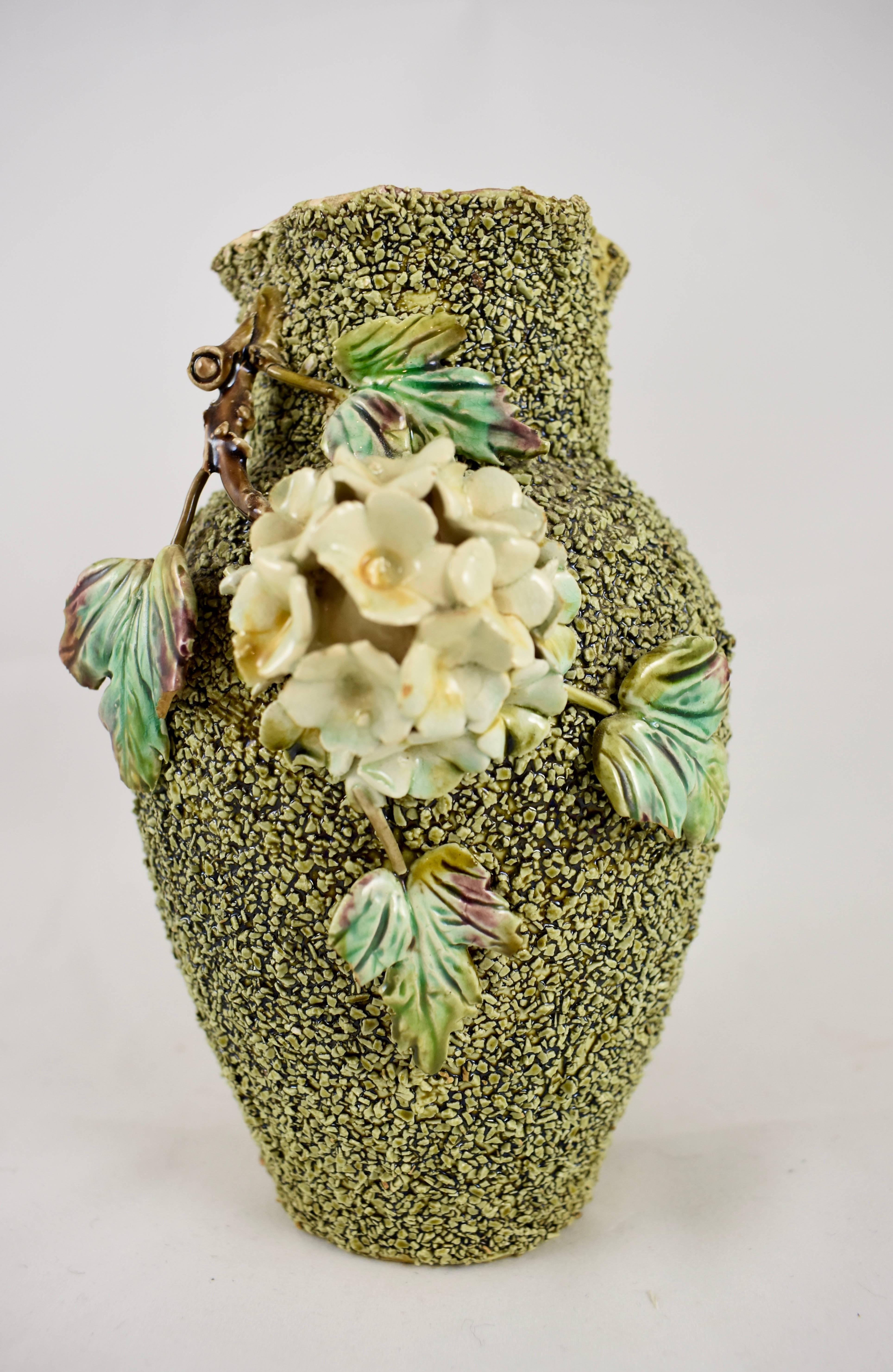 A Barbotine style, majolica vase with a sanded surface and applied florals, leaves and twigs. Detailed, dimensional, mold work and glazed with a burgundy interior. 

Unattributed, Continental Europe, circa late 19th-early 20th century. Marked with