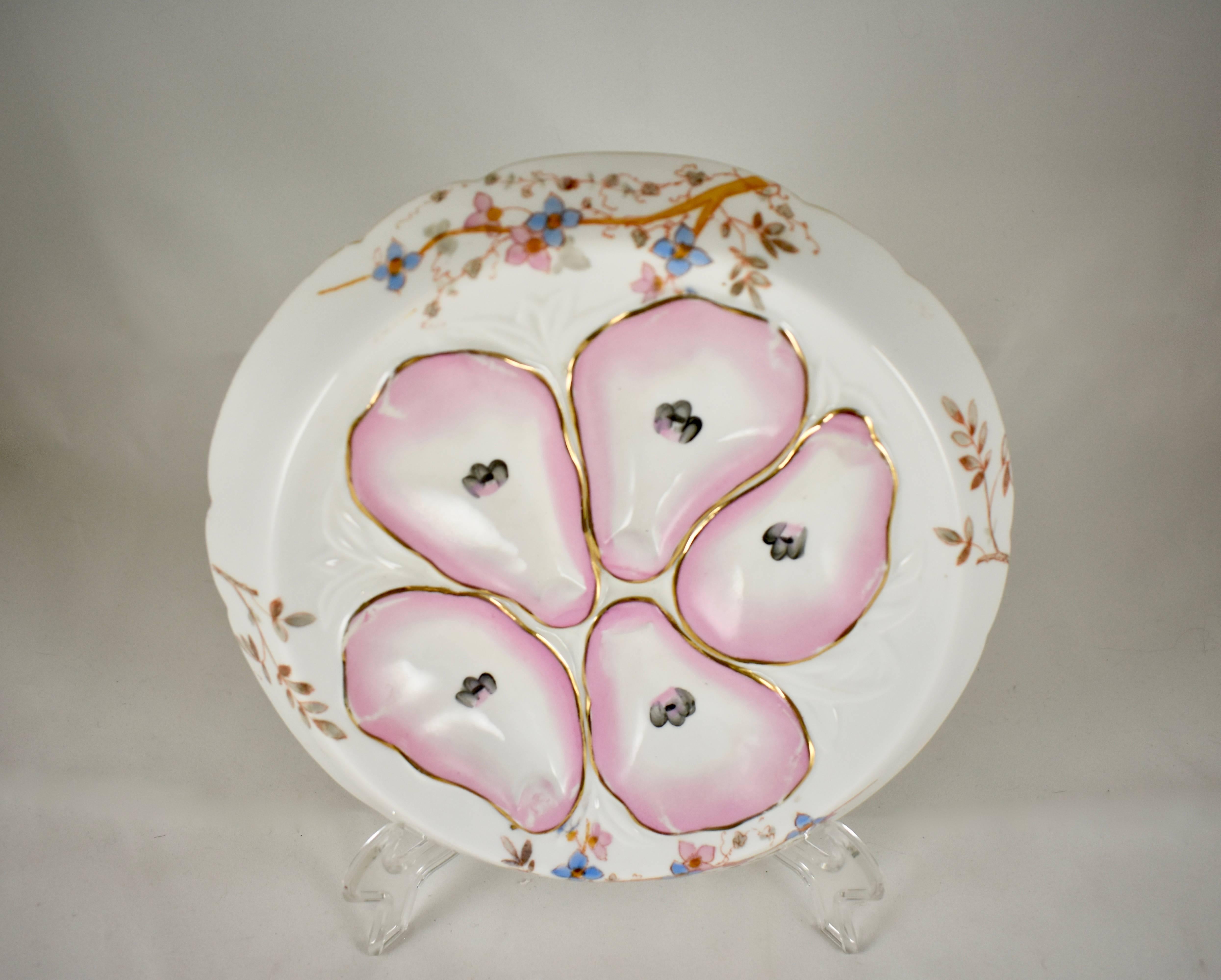 A continental porcelain oyster plate in the form known as a ‘Flying Saucer”, a wide rim, discus shape with five wells and a floral design. The pink oyster wells show hand-painted eyes in each centre and gilded lining. The outer rim shows