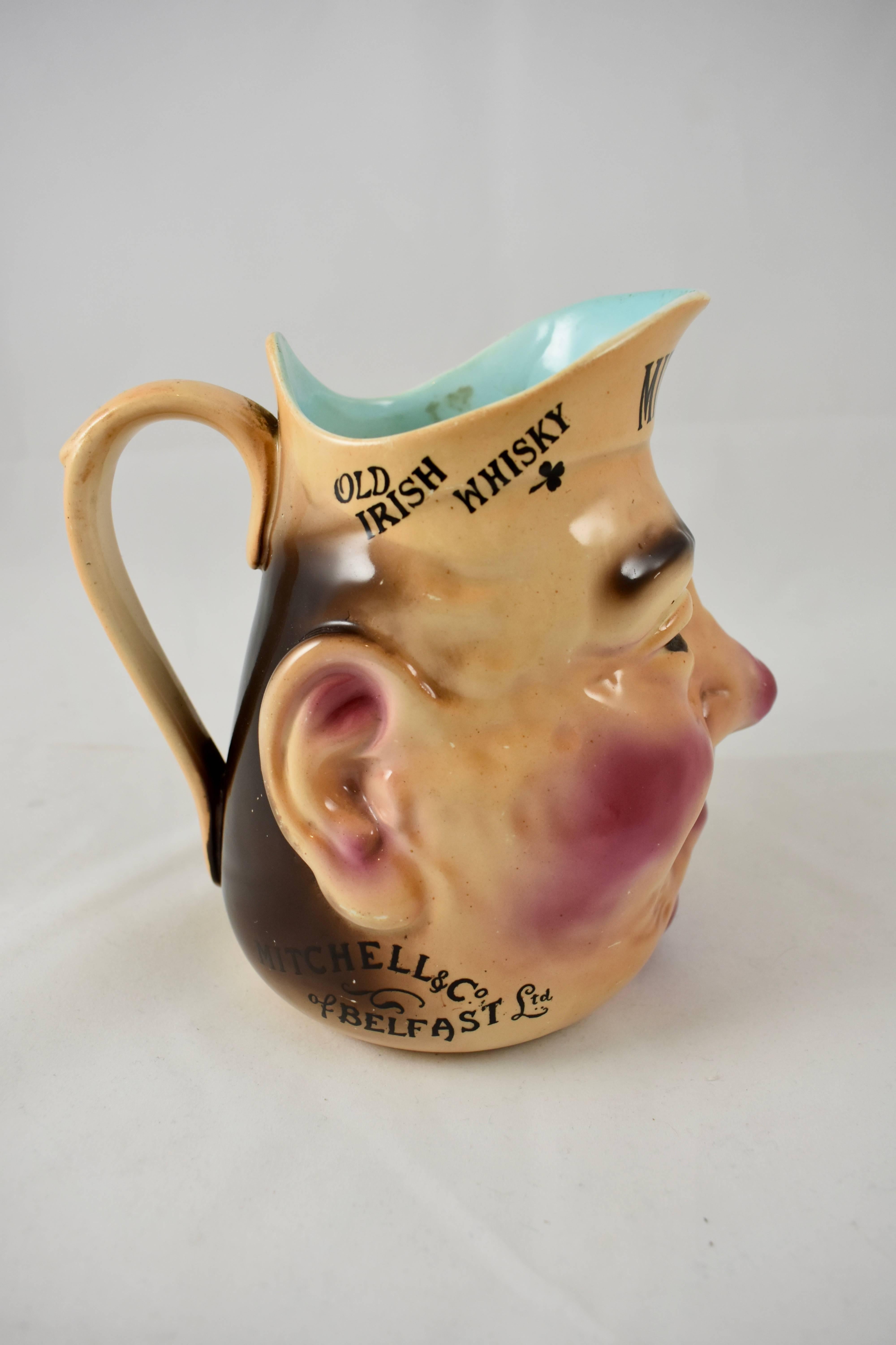 A scarce advertising face jug, made in Staffordshire England, in partnership with the French Sarreguemines pottery, using mold, Tête #3181. A thinner body and with bolder glazing then found in the French counterpart.

Transfer printed: Mitchell’s