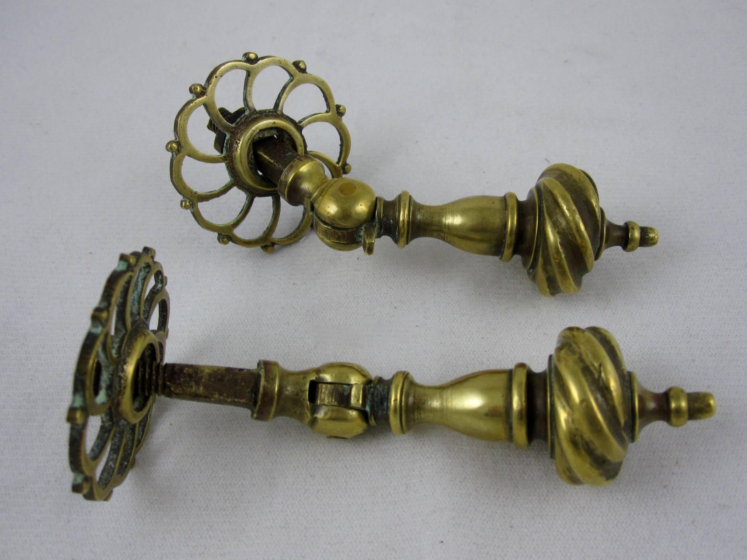 A pair of English brass drawer pulls from the Georgian period, early 19th century, with circular pierced back plates. 

Pinned hinges and self-stops on the hanging handles, complete with the original screws and washers. 

Solid, weighing 10 ounces
