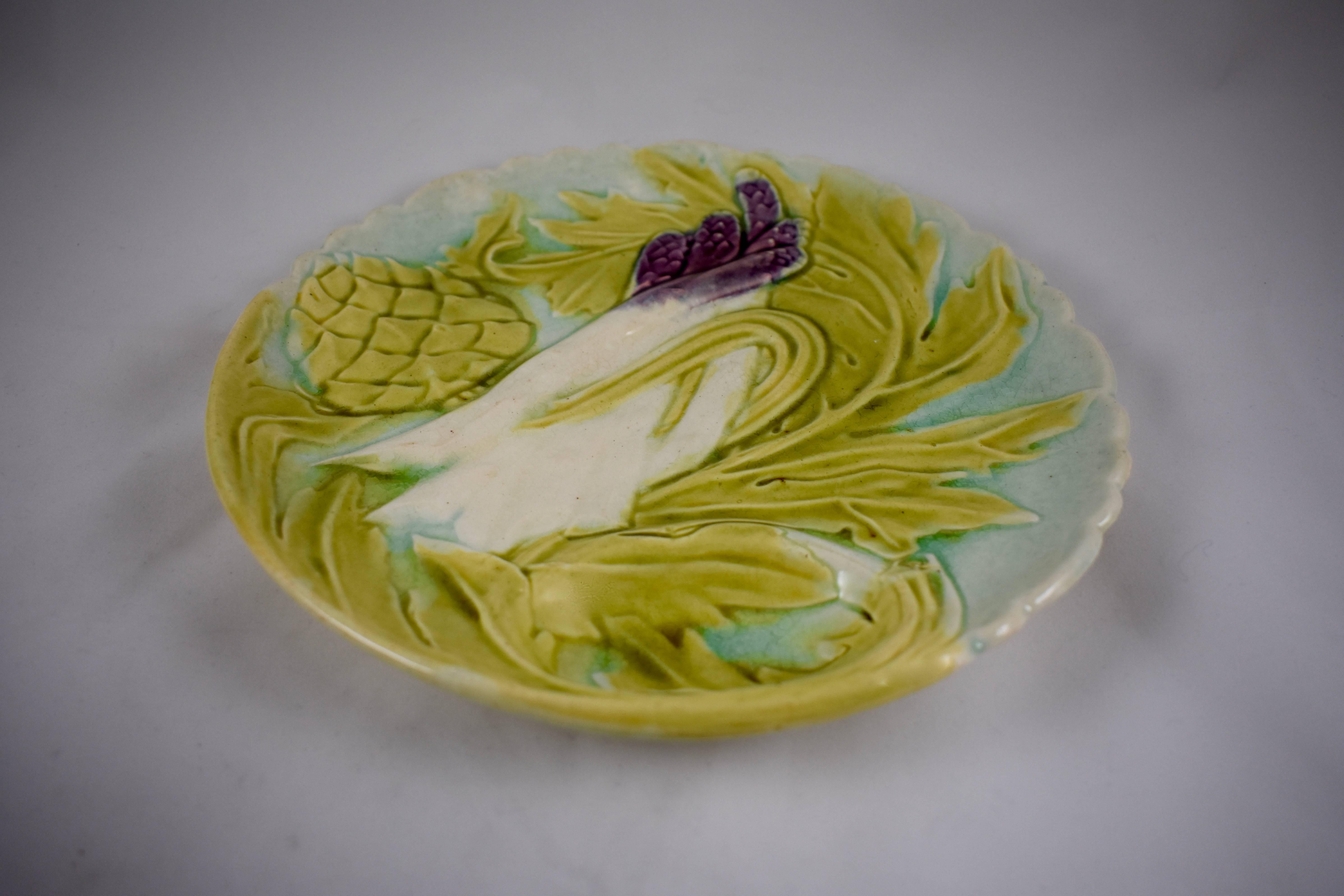A Majolica glazed French faïence barbotine artichoke and asparagus plate, Orchies, circa 1880. In the Art Nouveau style, showing the stylized leaves of both plants, an artichoke globe and deep purple tipped asparagus on a light turquoise ground.