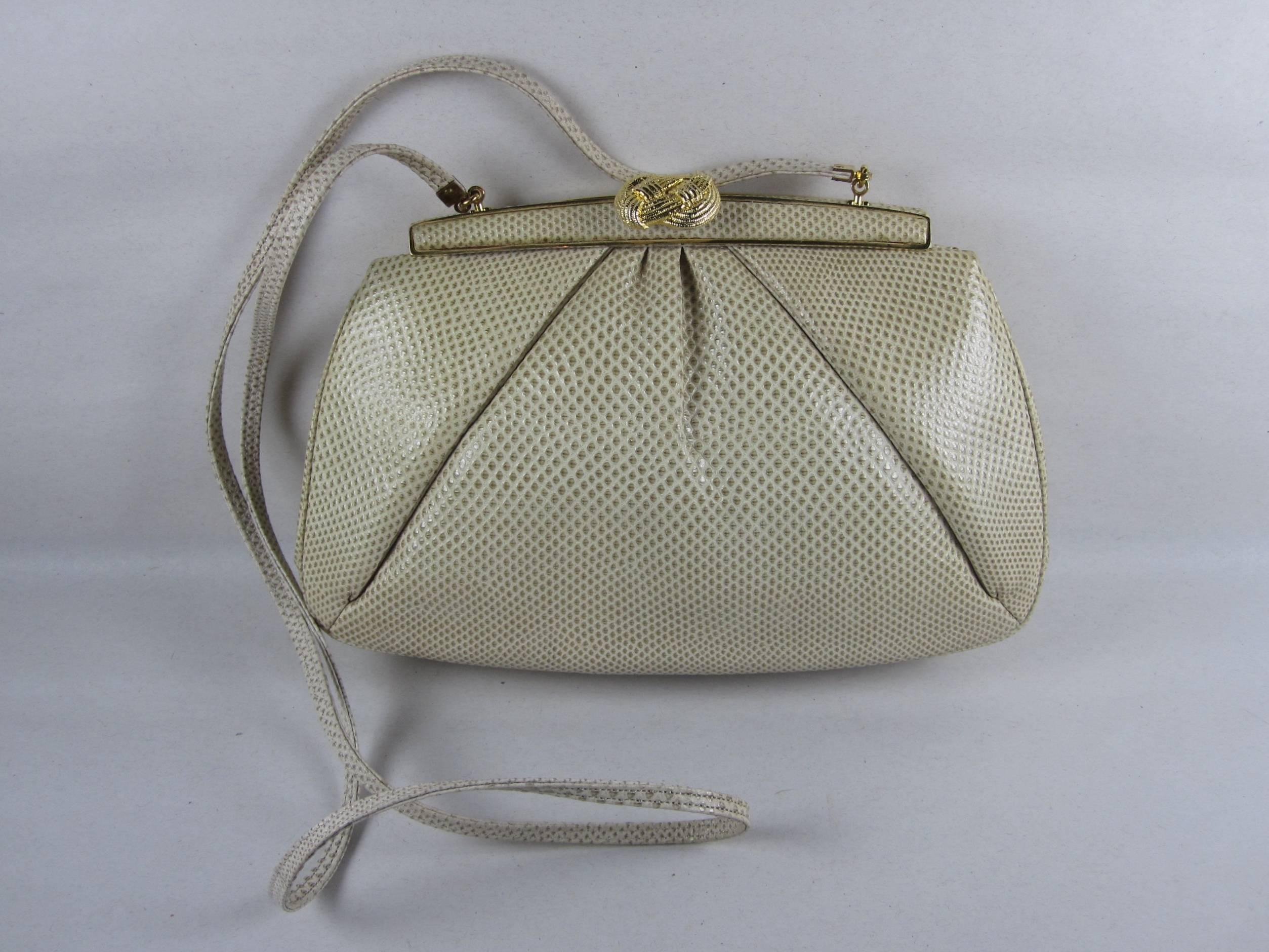 A Judith Leiber 1980's Vintage Taupe Lizard evening bag with a Gold-tone Knot clasp, metal trim and hinge, and a tuck-away lizard strap. Interior zippered compartment and side pocket. Comes with the duster bag and the original box. Excellent
