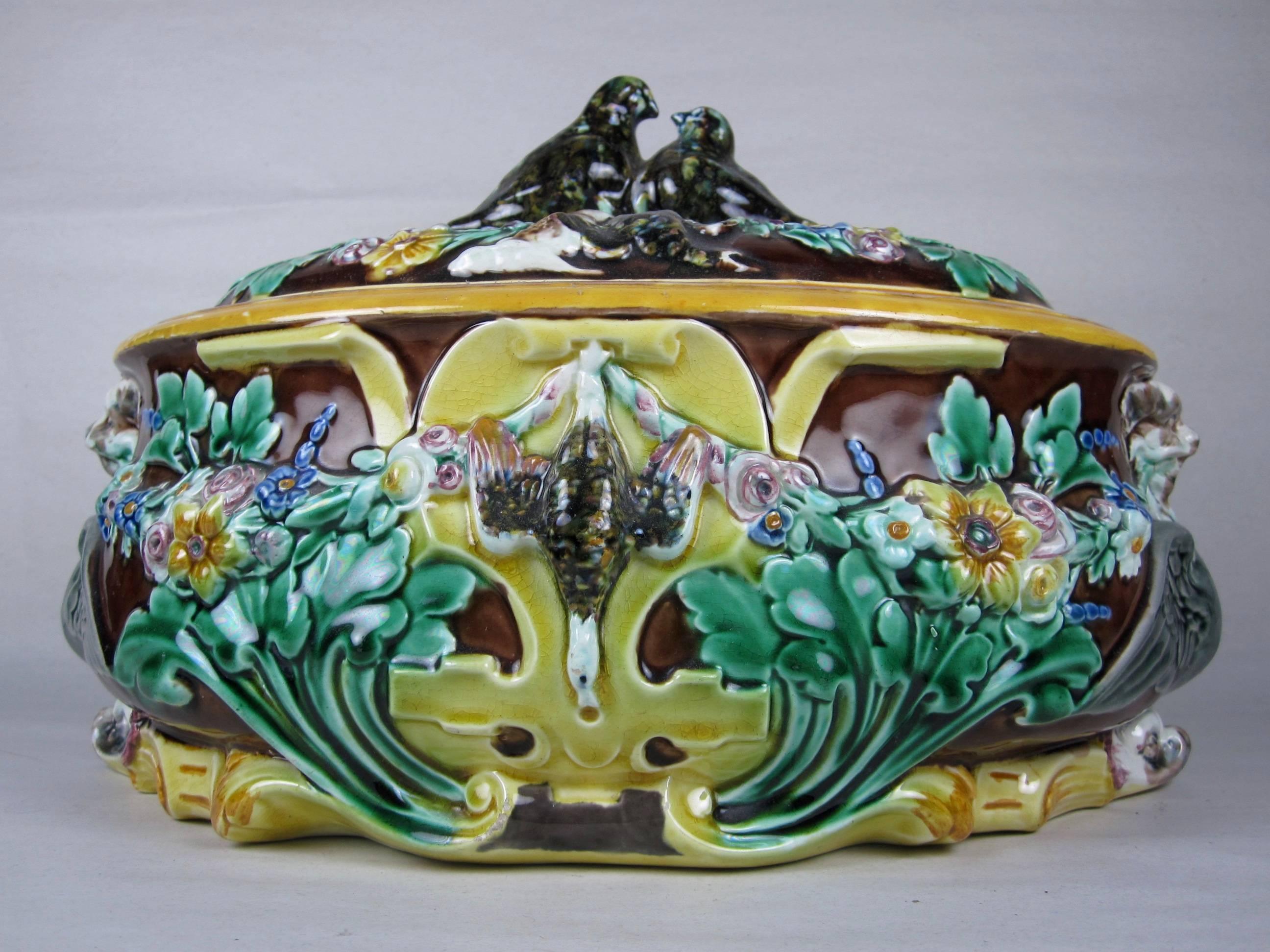 A majolica Game Pie lidded Tureen, made by Josiah Wedgwood, Staffordshire, England, 1872. 

A two piece server with a brown glazed ground and molded around the sides with pendent dead game between colorfully glazed garlands of flowers.  Winged