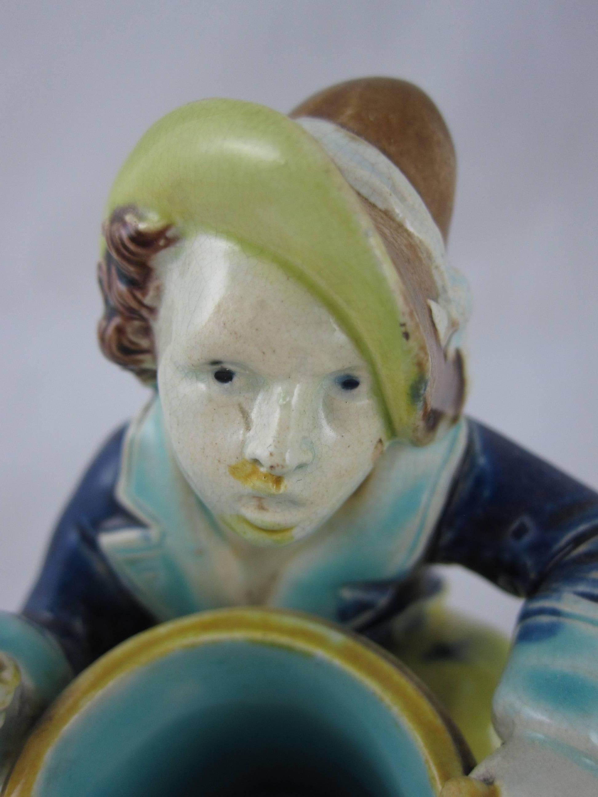 A rarer majolica figural match striker and holder, signed - Joseph Holdcroft, Staffordshire, England, circa 1835. 

The drummer boy figure is in period dress, the drum serves as the match holder, the tread on the underside of the boy’s left boot is