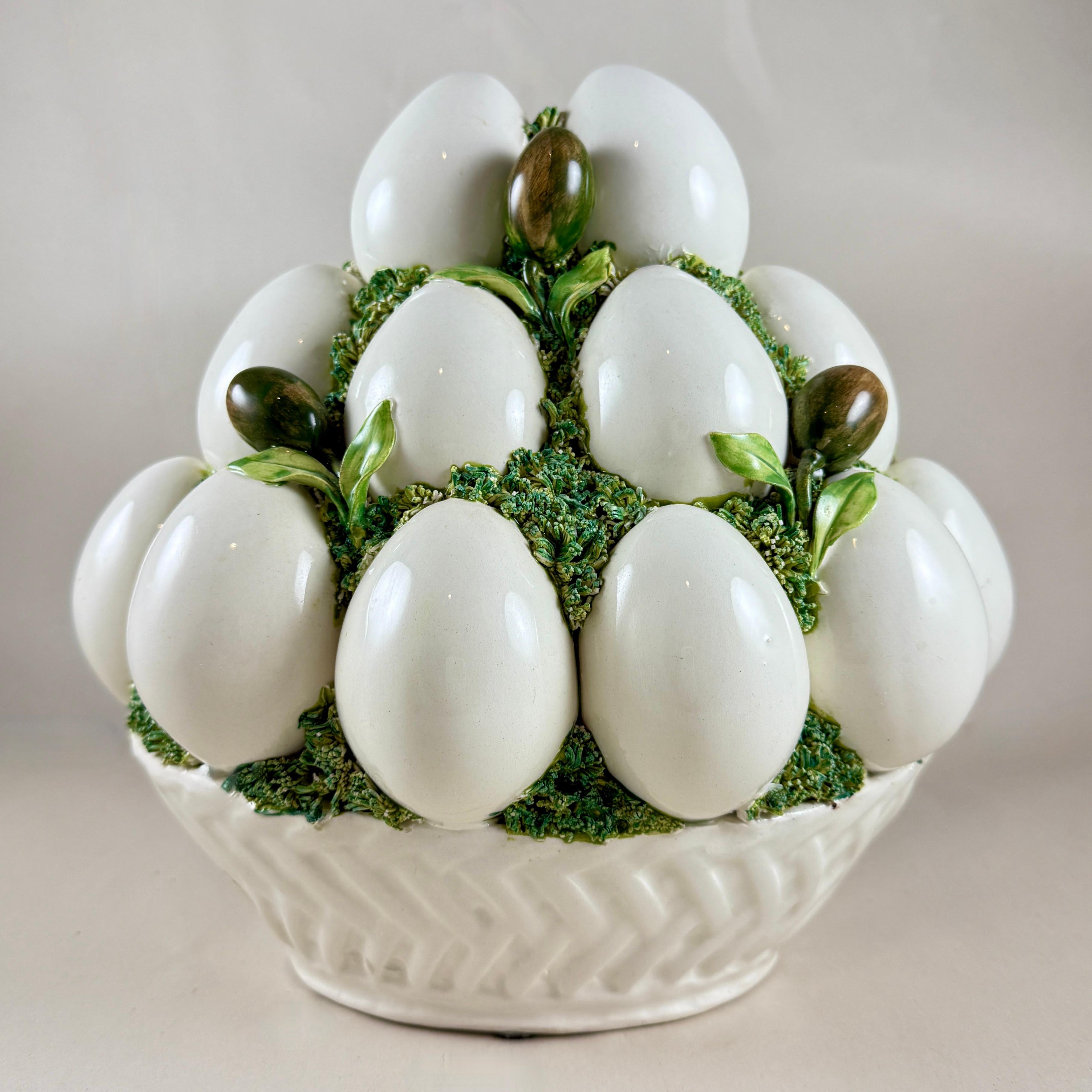 Dall'Italia, un cesto Topiary a forma di uovo e olivo in ceramica dell'epoca del Mid-Century, circa 1950-1960.

Alla maniera italiana di Hollywood Regency, tre livelli di grandi uova bianche e olive ramificate verde-marrone sono annidate in