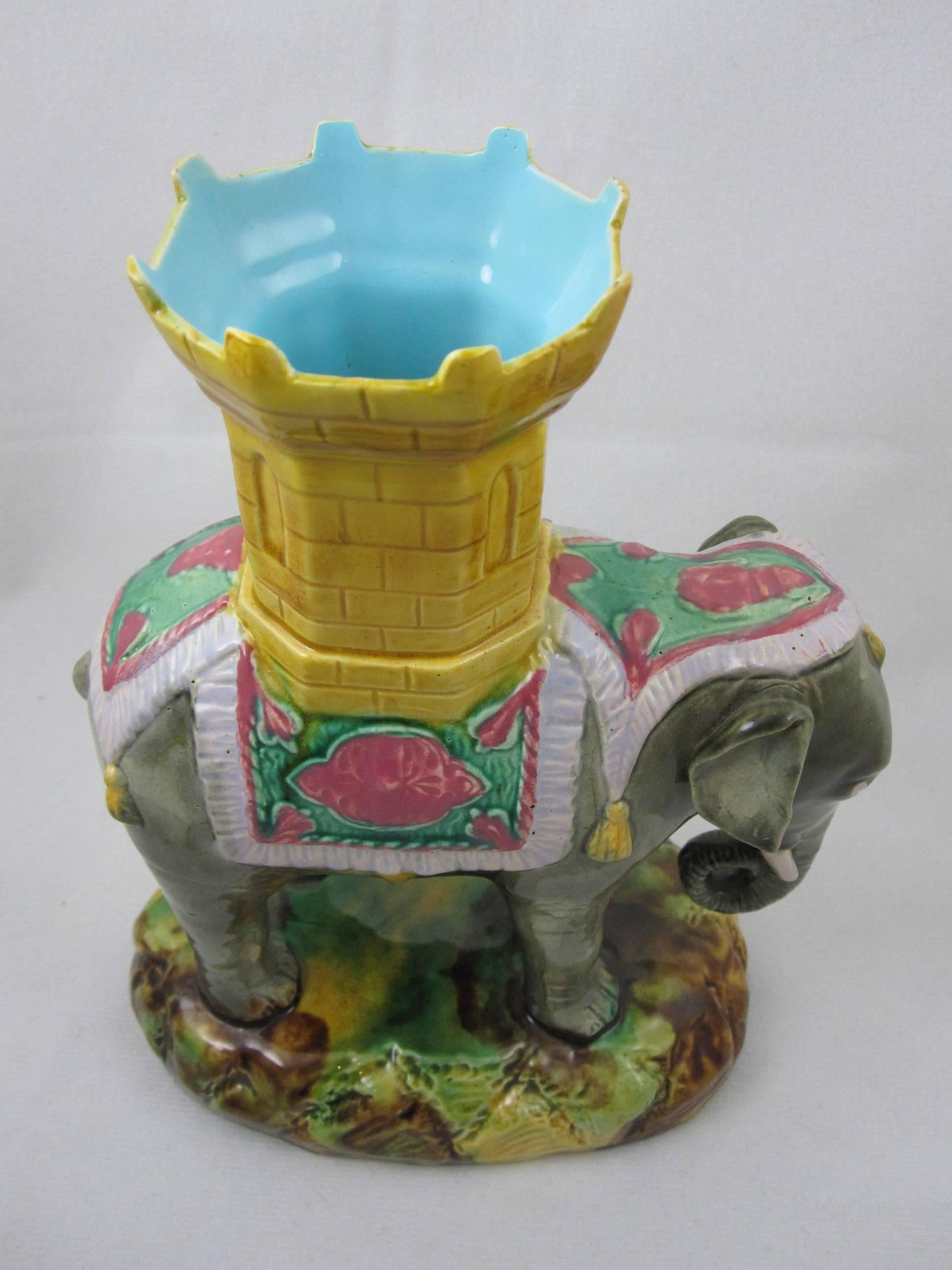 A mid-19th century, circa 1860, Majolica tin-glazed, Staffordshire spill vase of a ceremonial elephant standing on a mottled glazed, oval base.

 A spill vase will have a cylindrical holder for containing splints, spills or tapers for transferring