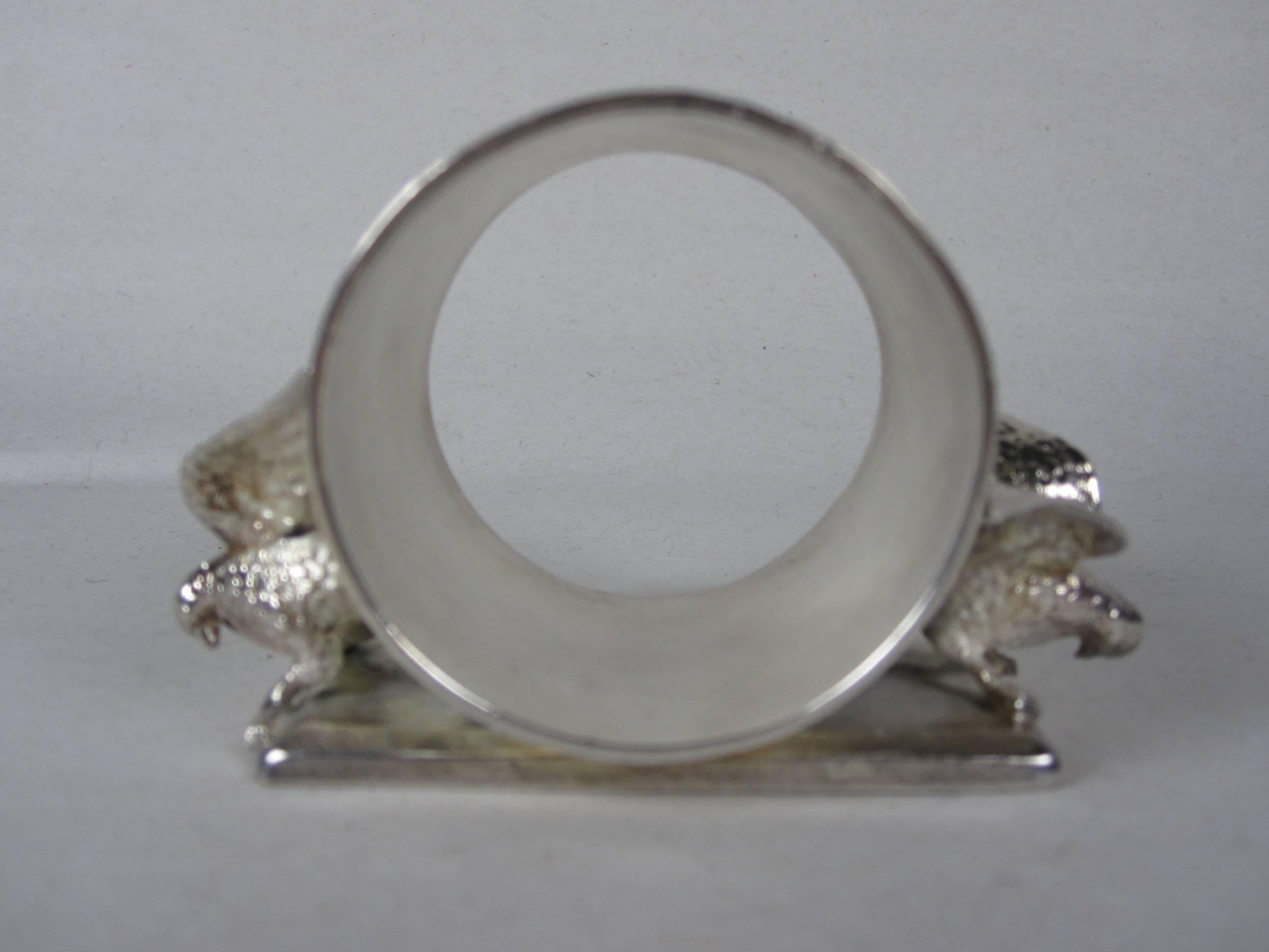 An antique Victorian Era silver plate standing napkin holder with a pair of spread winged birds on either side of an engraved floral ring on a rimmed base. 

Dating from 1890-1910. Marked “Rogers Bros. Silver, Meriden Conn.”

Light wear.