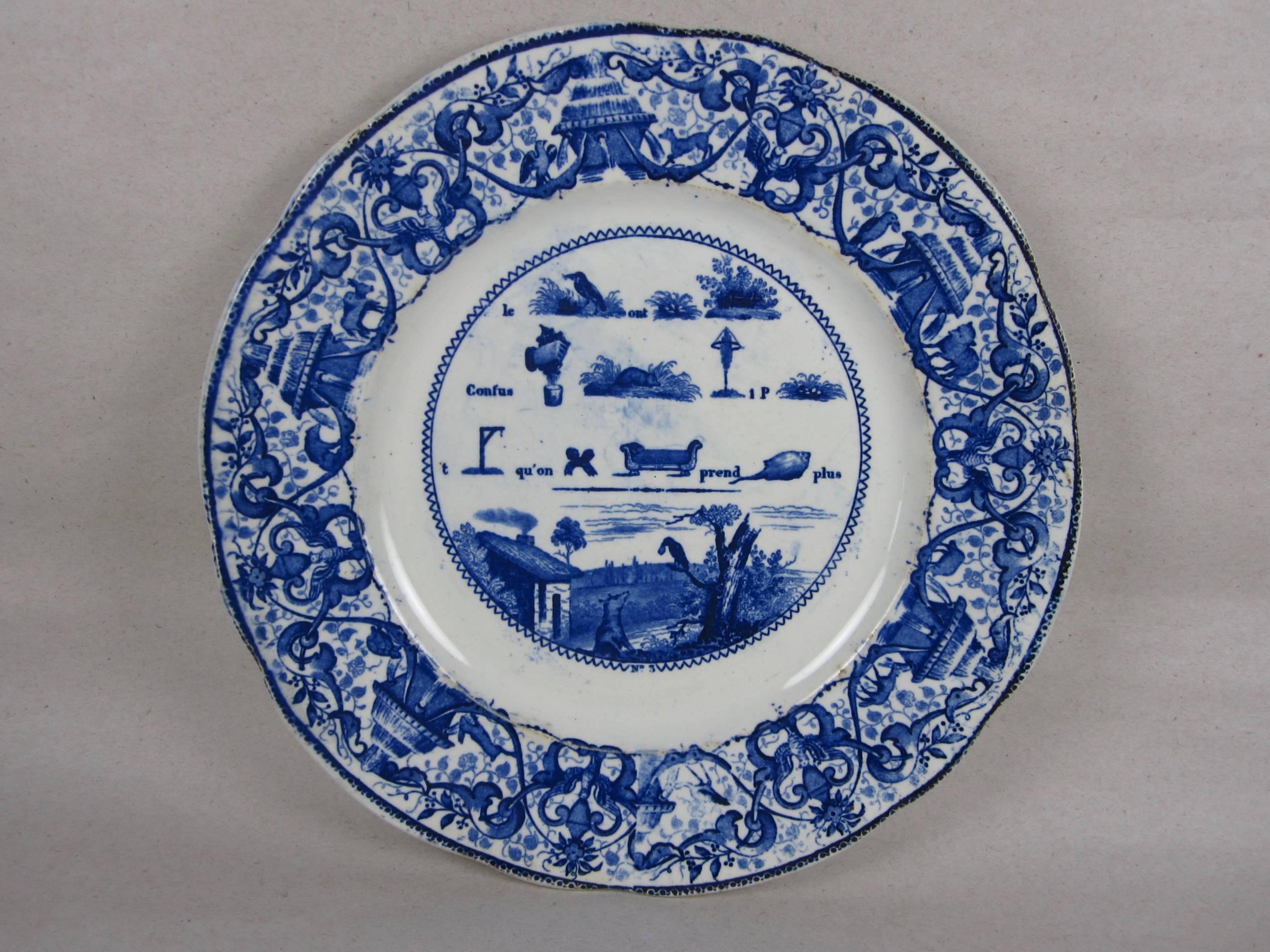 A set of four French Rebus puzzle dessert plates, transfer printed in Cobalt blue on a white, opaque porcelain body. Most often printed in black on white, the blue transfer makes this a rarer set. When solved, the picture puzzle spells out a wise