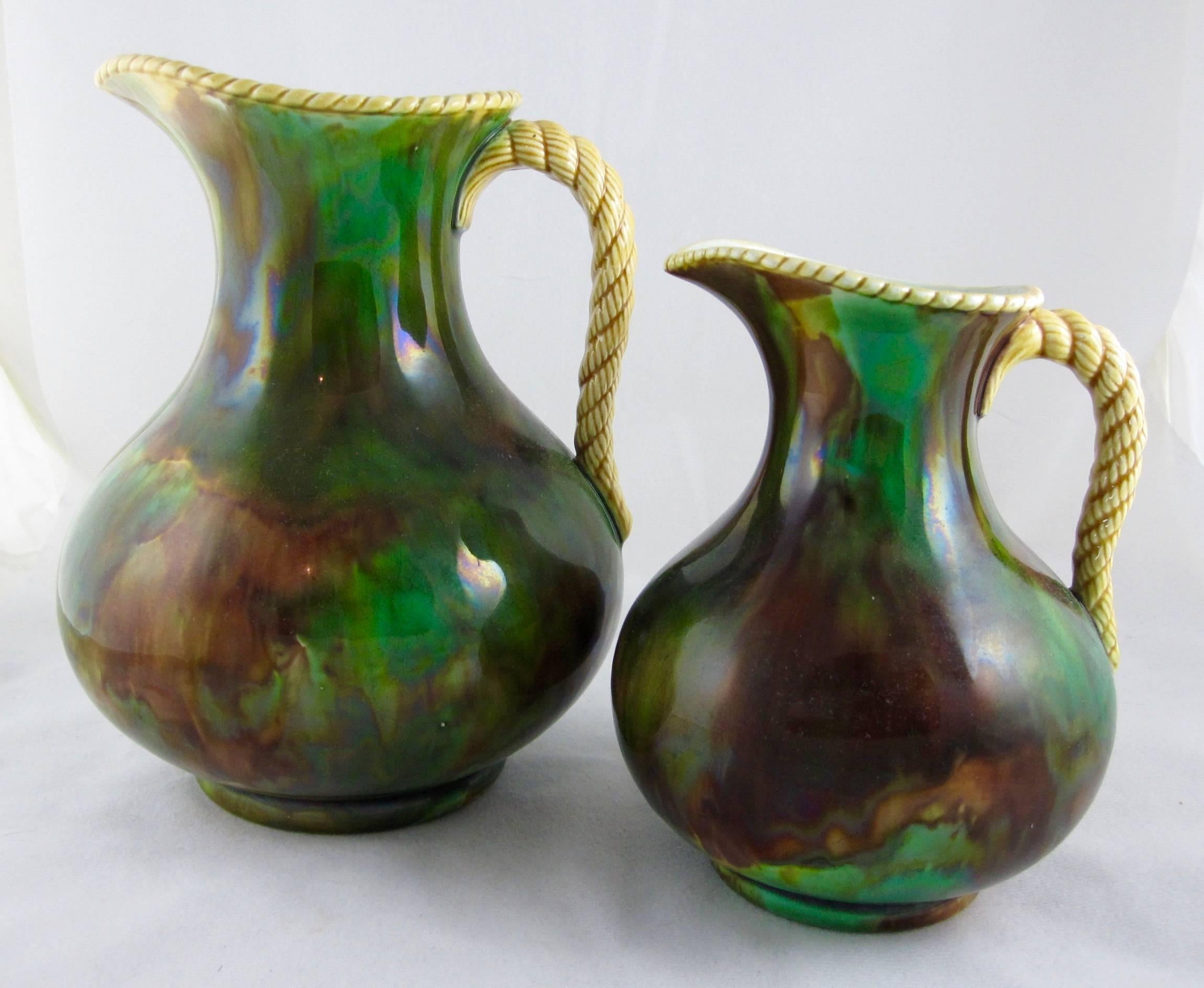 A pair of Majolica jugs, marked Wedgwood with the date cipher AVS for the year 1864.

The bulbous bodies are finished in a mottled glaze meant to imitate tortoise shell. They each have a twisted rope applied handle and rim glazed in a yellow