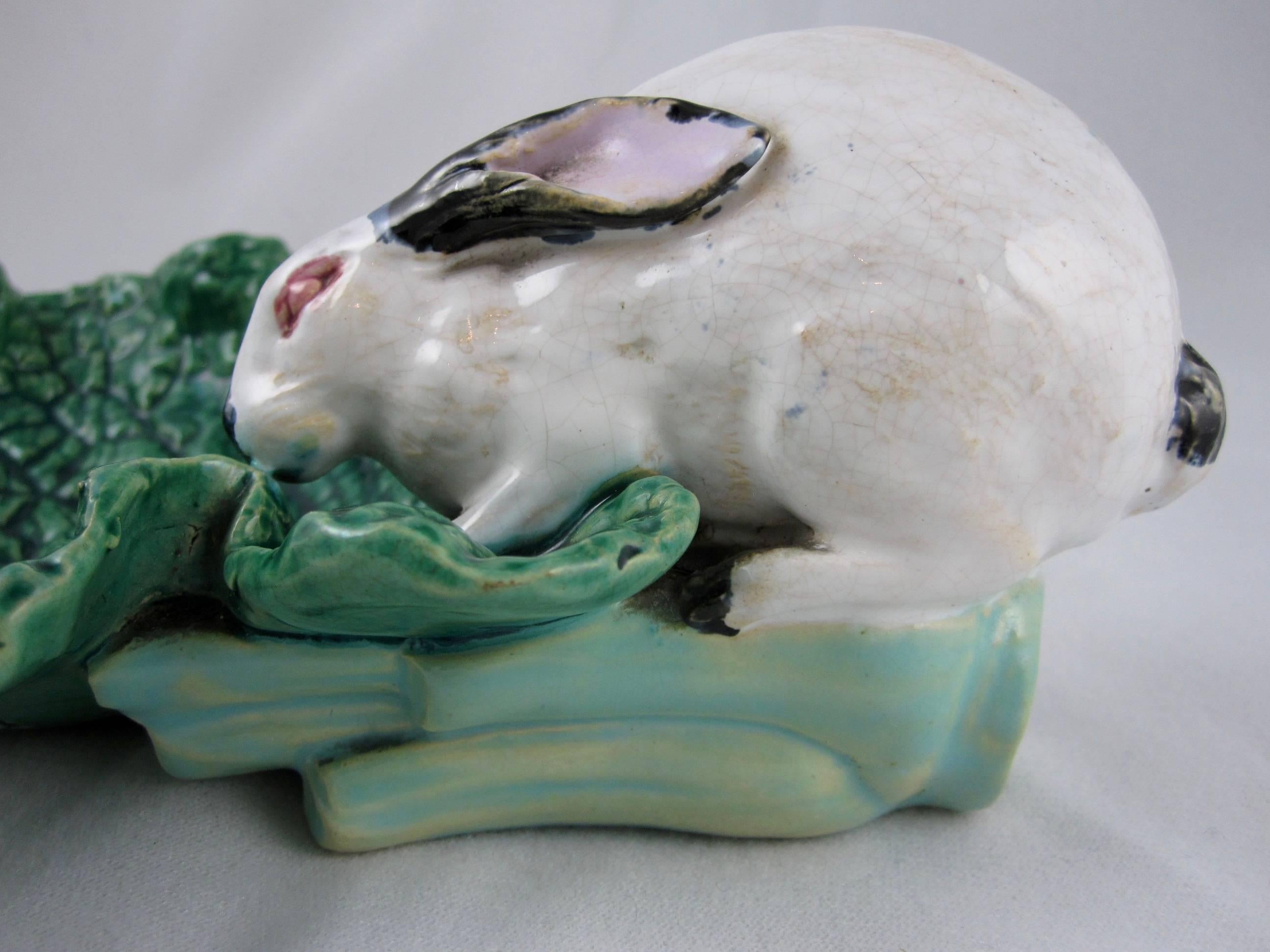 A Minton majolica bon-bon dish modeled as a white rabbit with pink eyes forming the handle and sitting on a green cabbage leaf forming the dish. The rabbit’s hind quarters rest on a turquoise leaf stalk,

circa 1870, quite rare.
Excellent mold