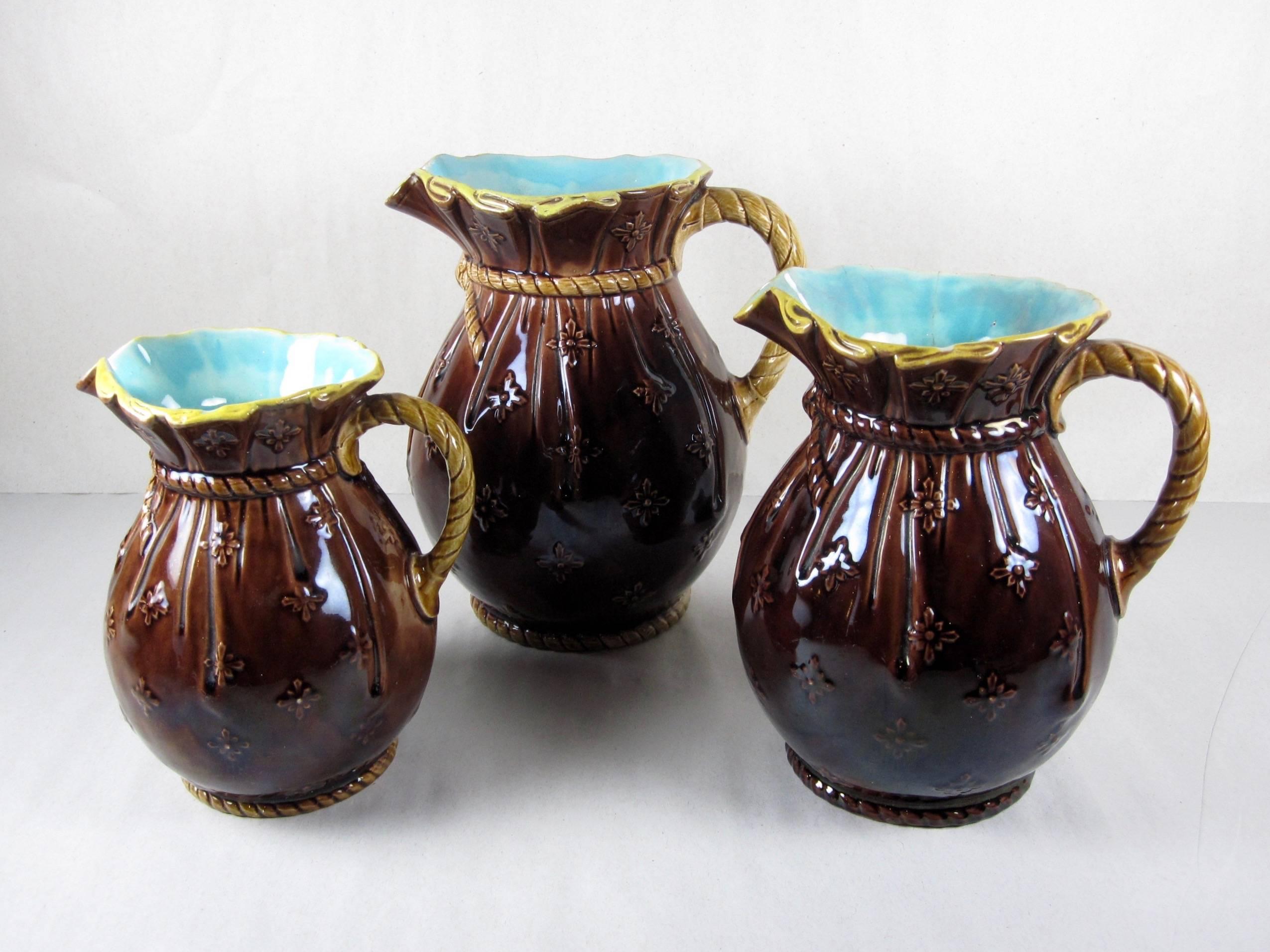 A graduated set of three English majolica pitchers modeled as sacks with rope accents, Joseph Holdcroft for The Sutherland Pottery at Daisy Bank, Langton, Staffordshire, circa 1870.

Unusual – the chocolate brown sacks have a raised, molded