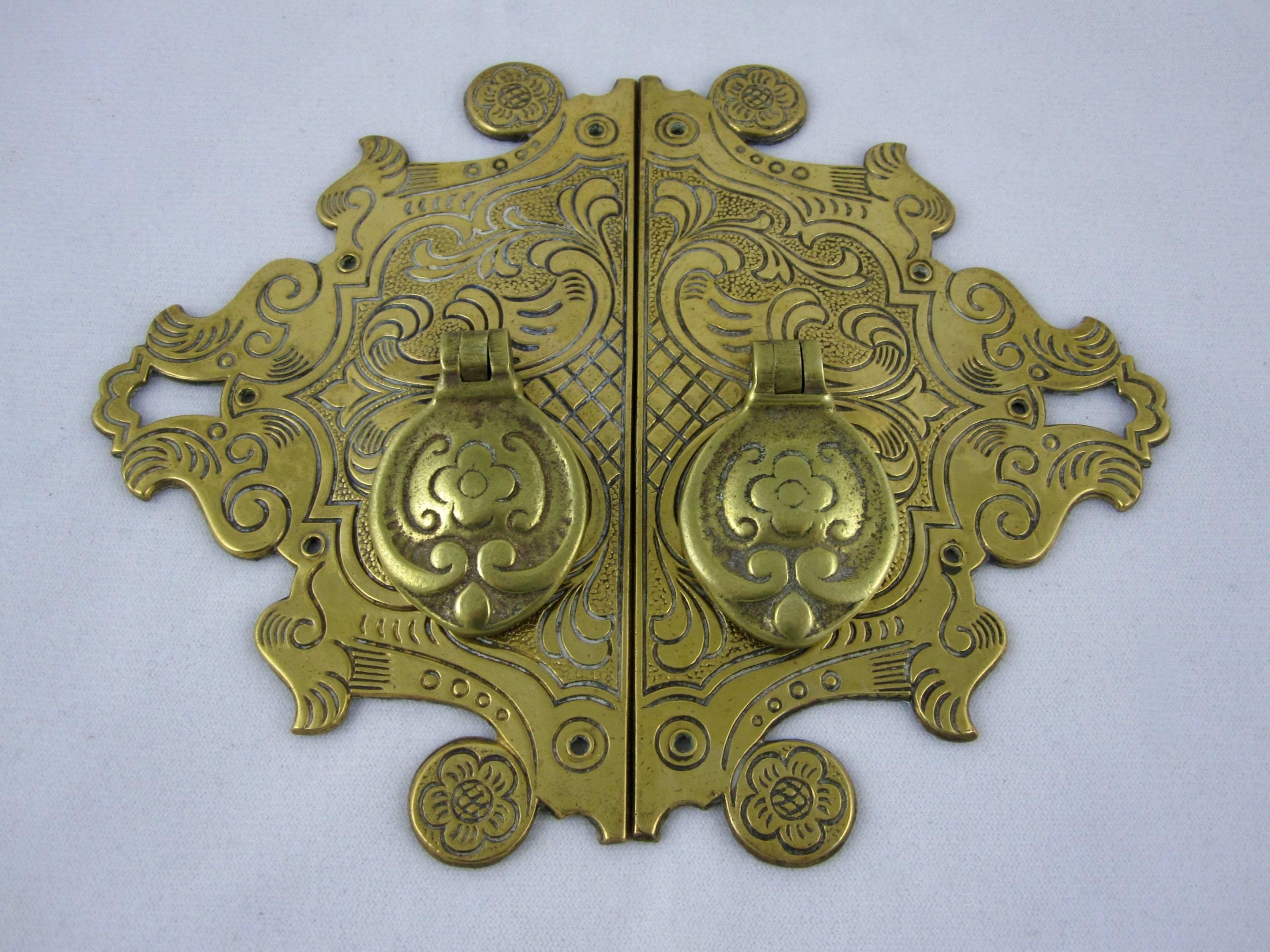 A pair of antique English brass cabinet pulls with back plates in an Asian influenced pattern, late 19th-early 20th century. The right and left shaped back plates have hinged hanging pulls.

 Marked on the back ‘Made in England’ No. 9994, a mold