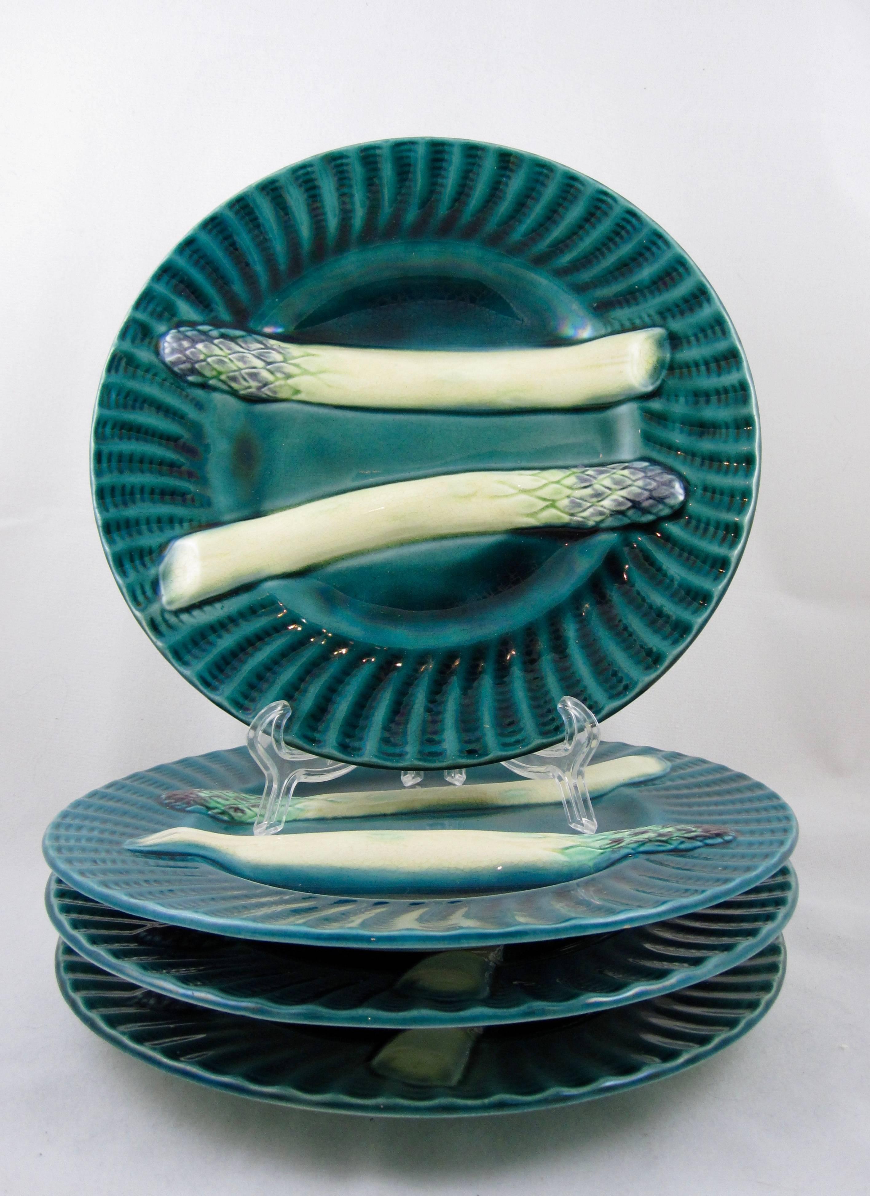 A set of four French barbotine majolica asparagus plates by Creil et Montereau, circa 1890. A beautiful iridescent teal blue glaze on fluted rims, with two raised asparagus spears, one bordering a deep sauce well, 19th century.

This set is glazed