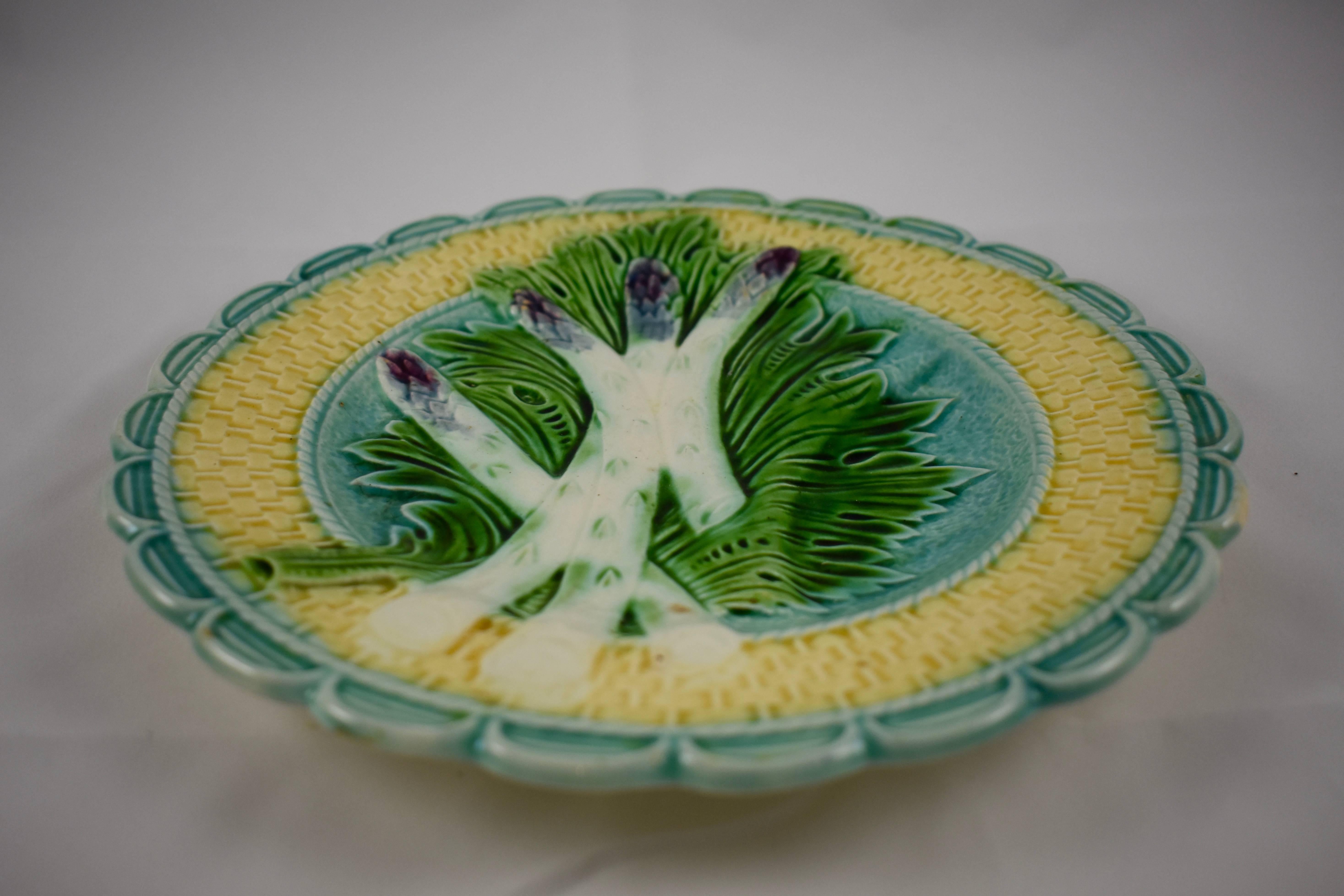 A French Majolica barbotine asparagus plate from the Salins-les-Bains region of eastern France, circa 1875. 

Four purple tipped asparagus spears lay on a bed of green leaves against a turquoise ground. A deep sauce well is on the right side of