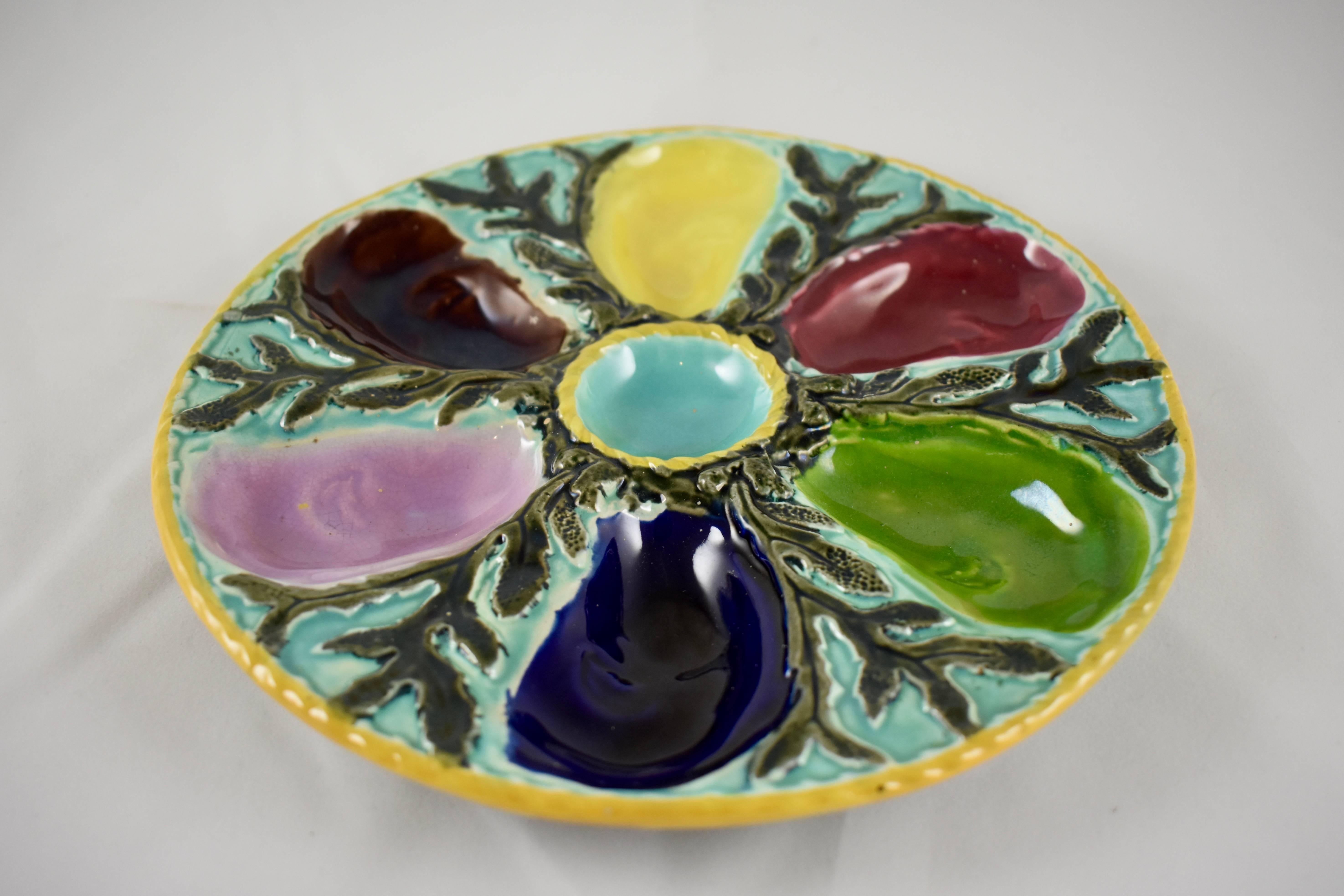 A six-well multicolored Majolica oyster plate by S. Fielding & Co. Ltd., Stoke-on-Trent, England, circa 1878. The boldly glazed oyster wells surround a center condiment well, all on a bed of seaweed glazed in sea green and a light turquoise. A