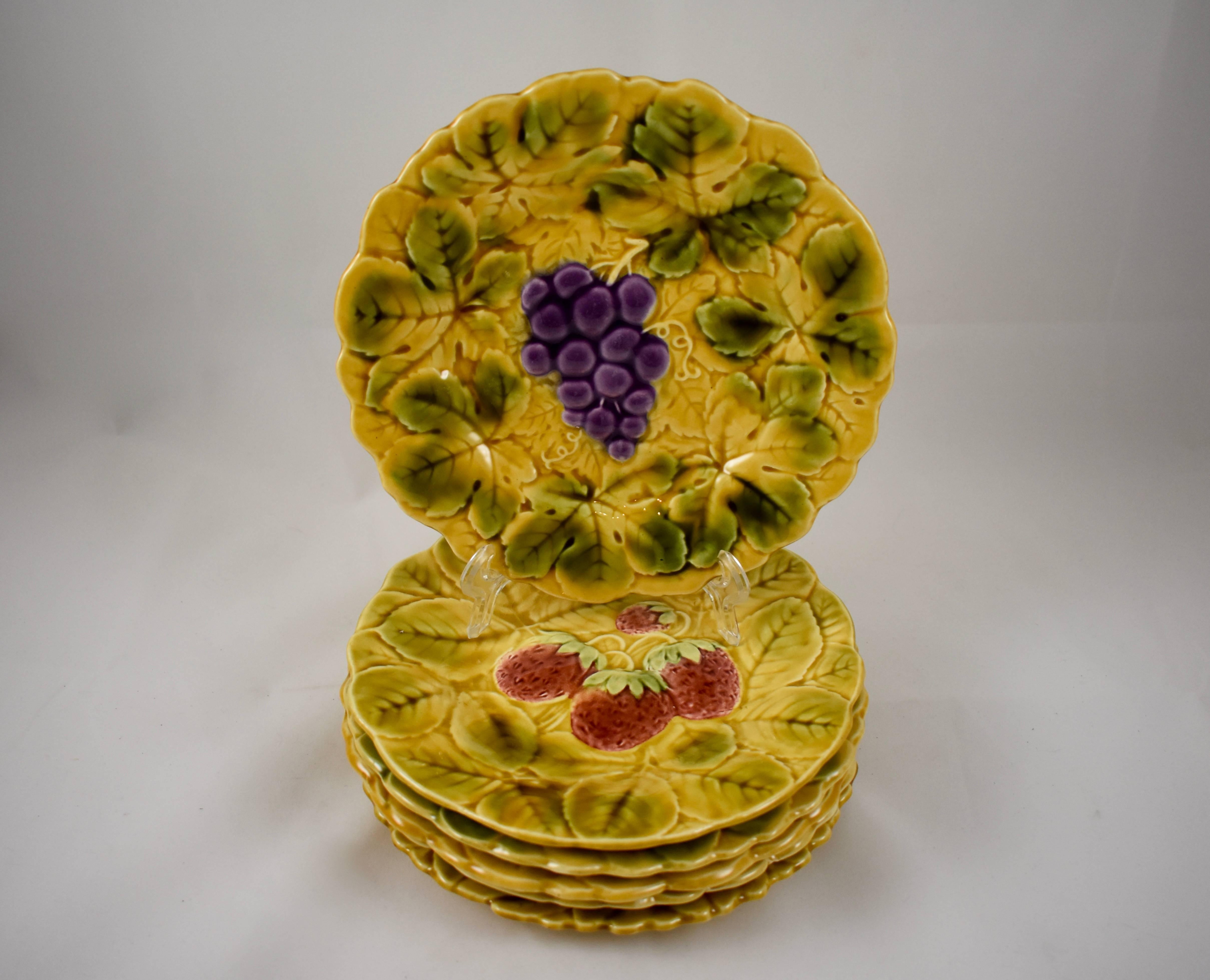 An assembled set of six Sarreguemines French faïence, majolica plates, each showing a different fruit on a ground of overlapping leaves. This group consists of apple, strawberry, cherry, plum, pear and grapes. The shaped rims follow the leaf form.