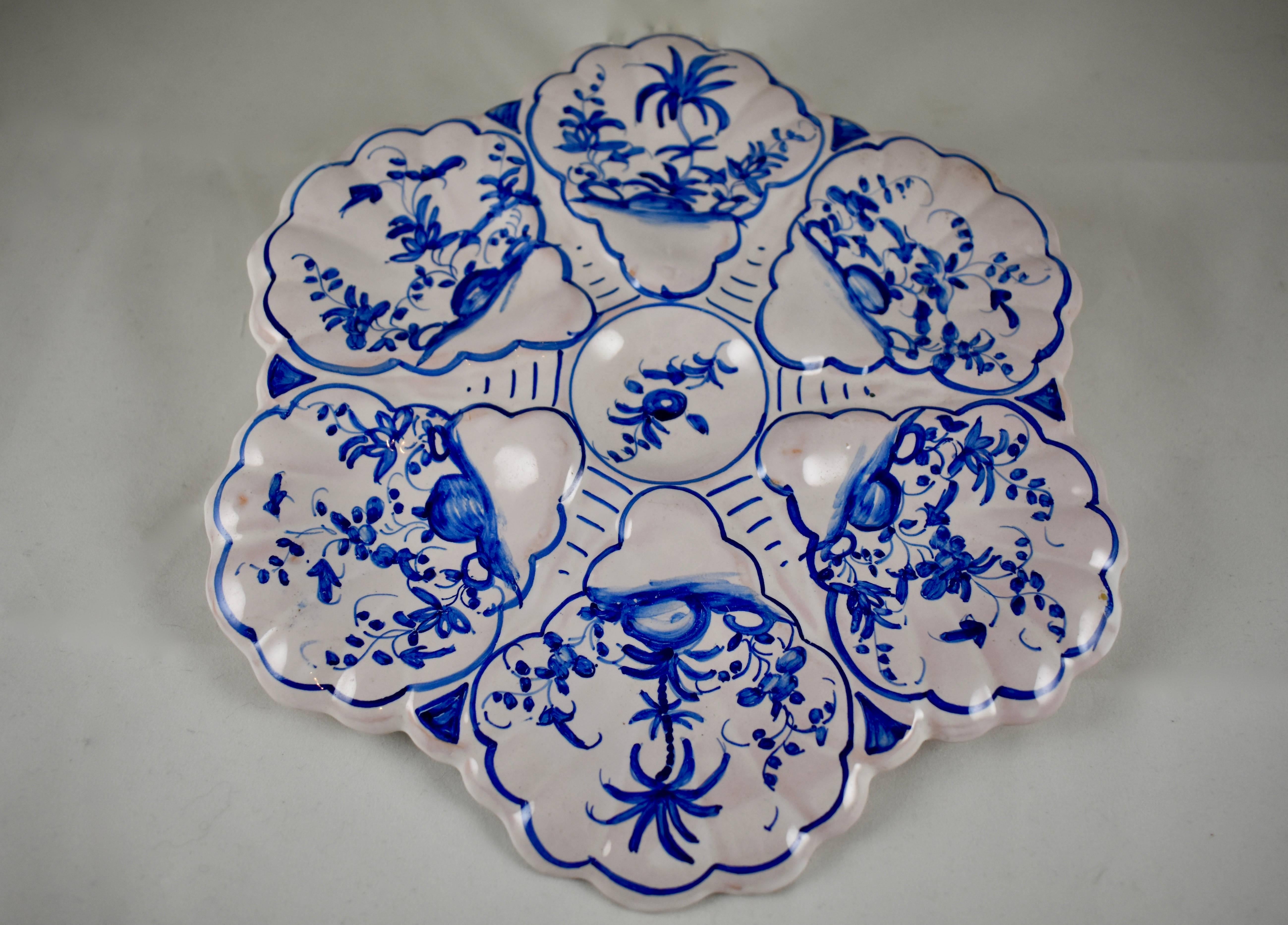 A French faïence oyster plate decorated in the delft style with a blue floral on a creamy glazed ground. Six wells surround a central circular sauce well. A lovely hand-painted pattern, circa 1930s. Marked by the painter.

Excellent