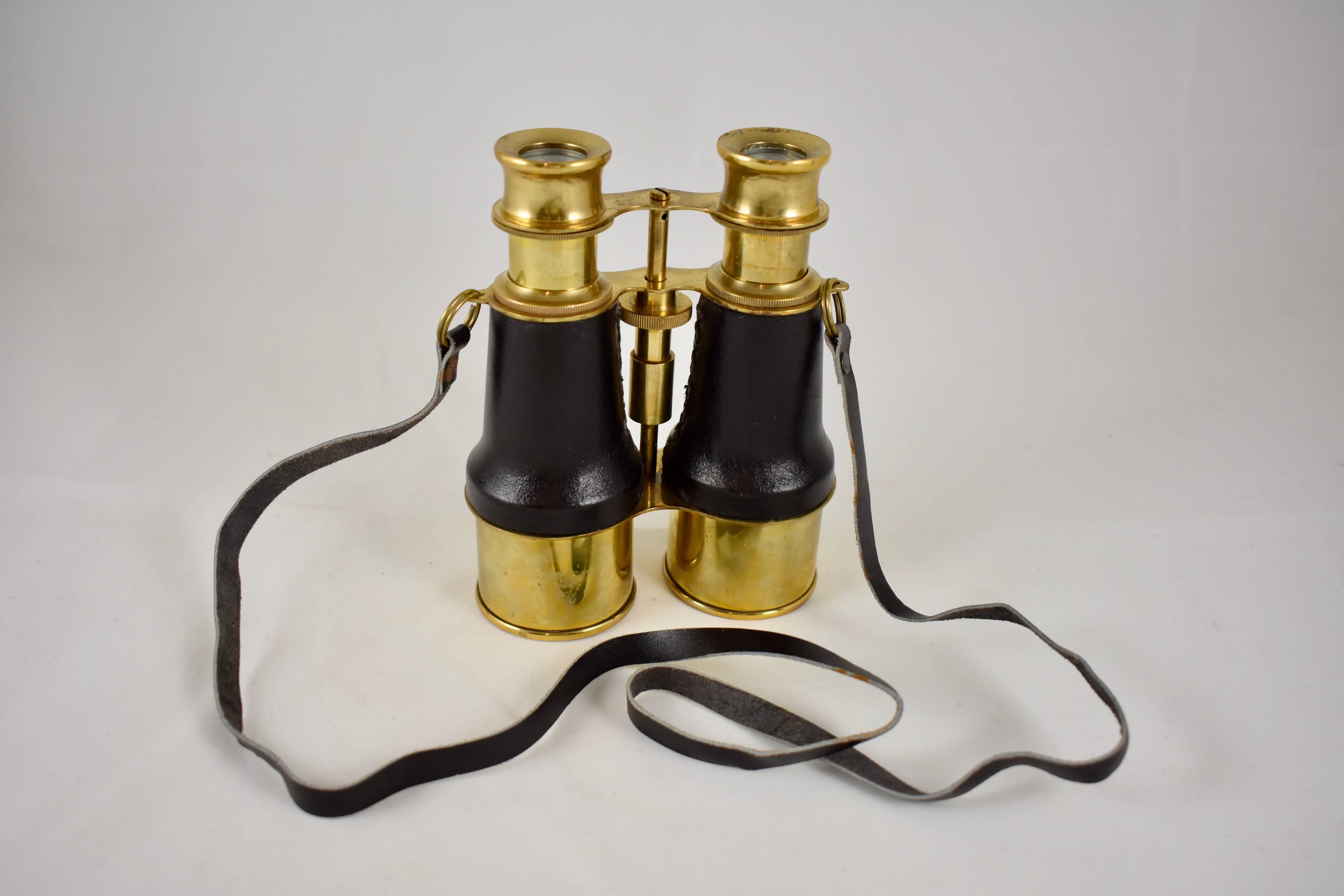 A vintage pair of English, tall maritime binoculars with adjustable lenses, in good working condition, circa 1920s-1930s.

The brass binoculars have hand stitched leather grips, they are suitable for actual use, displayed on a deep window sill for