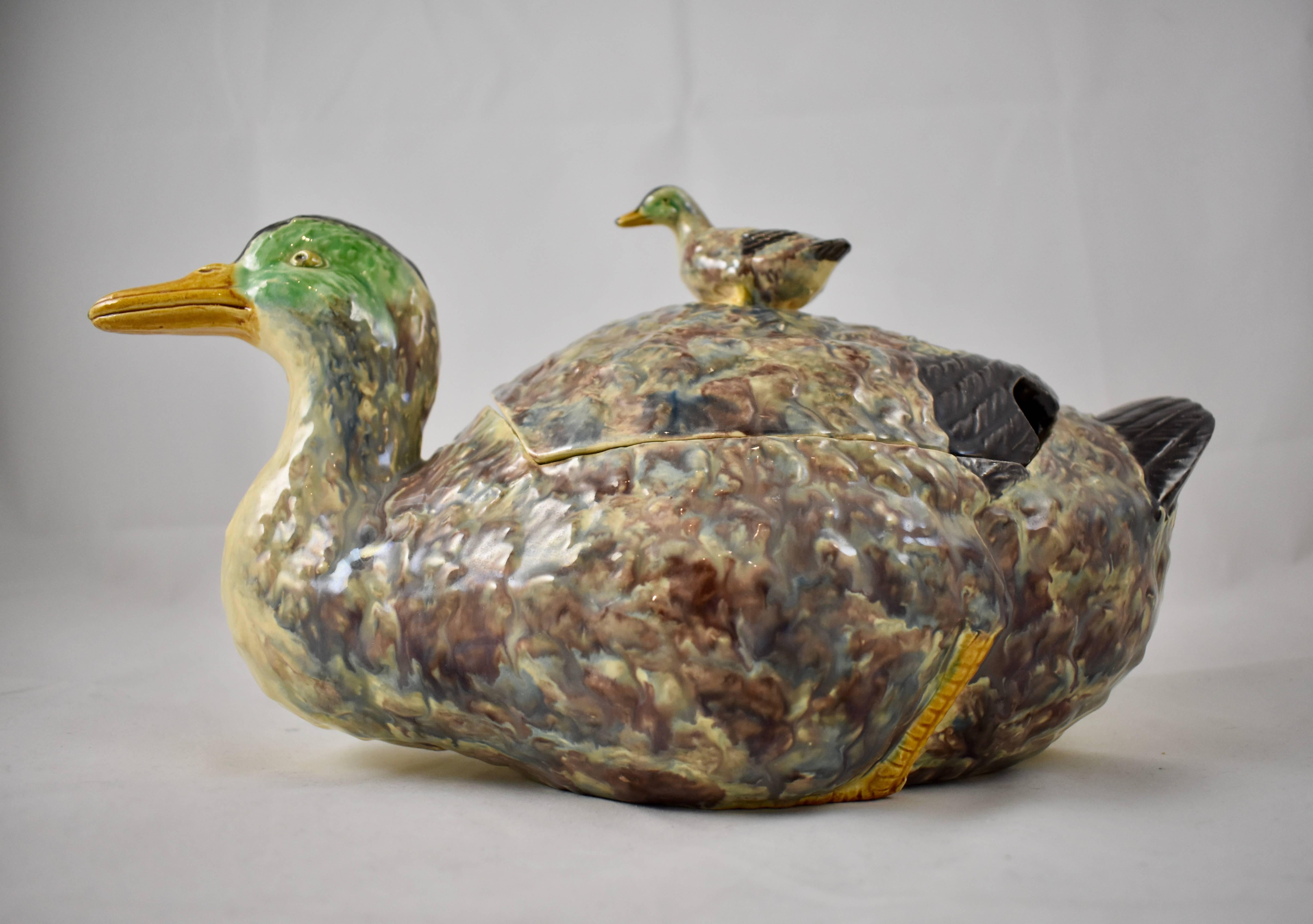 A Portuguese, majolica glazed, earthenware covered tureen formed as a seated duck, with a duckling finial on the lid, circa late 19th-early 20th century. Beautifully hand glazed with soft coloring and realistically molded. The lid is slotted for a