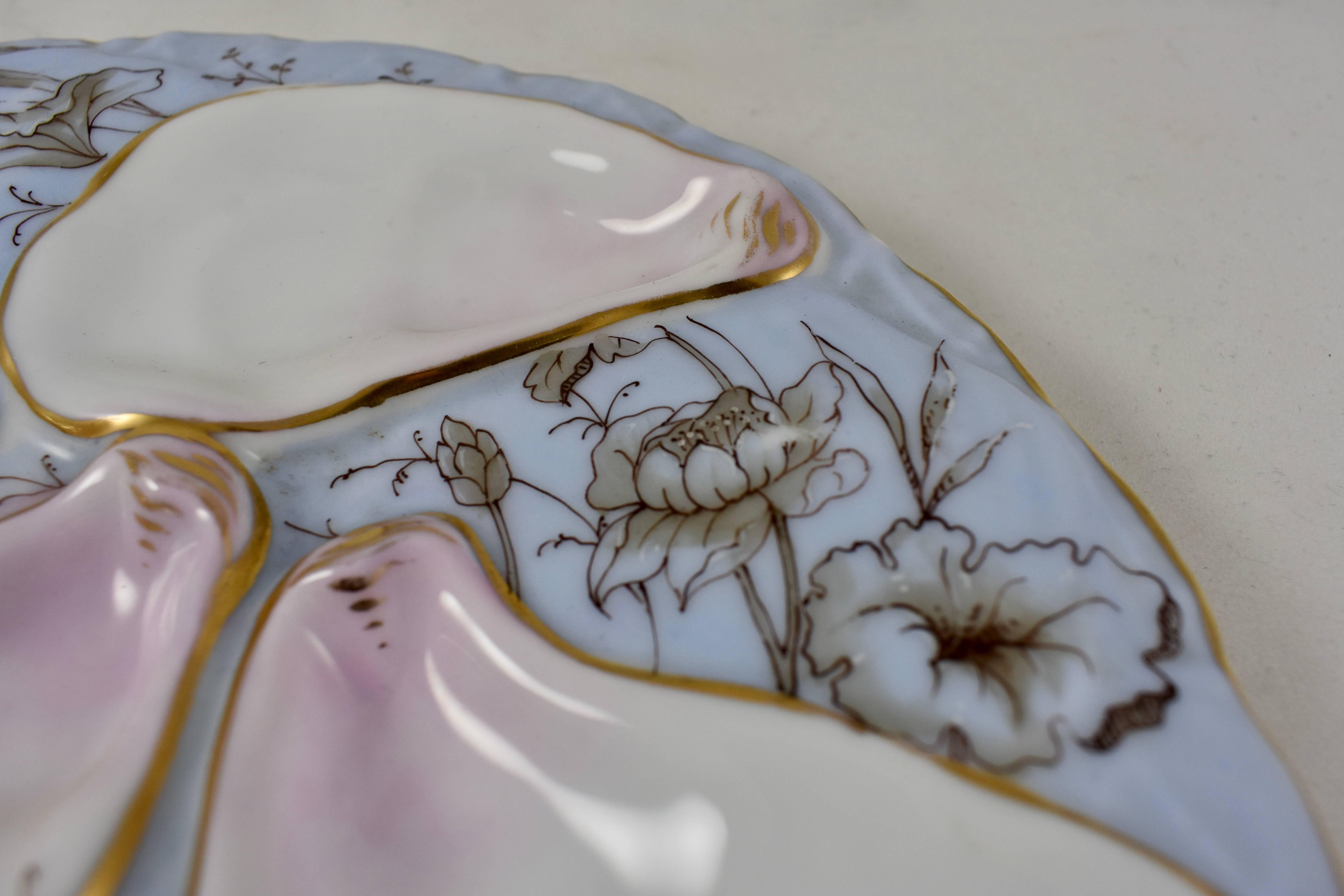 A late 19th Century porcelain, crescent shaped oyster plate, showing a hand-painted floral pattern on a periwinkle blue ground. Five oyster shells and two smaller cockle shells have a pink blush and gilded lining.

Marked with the red, iron- oxide