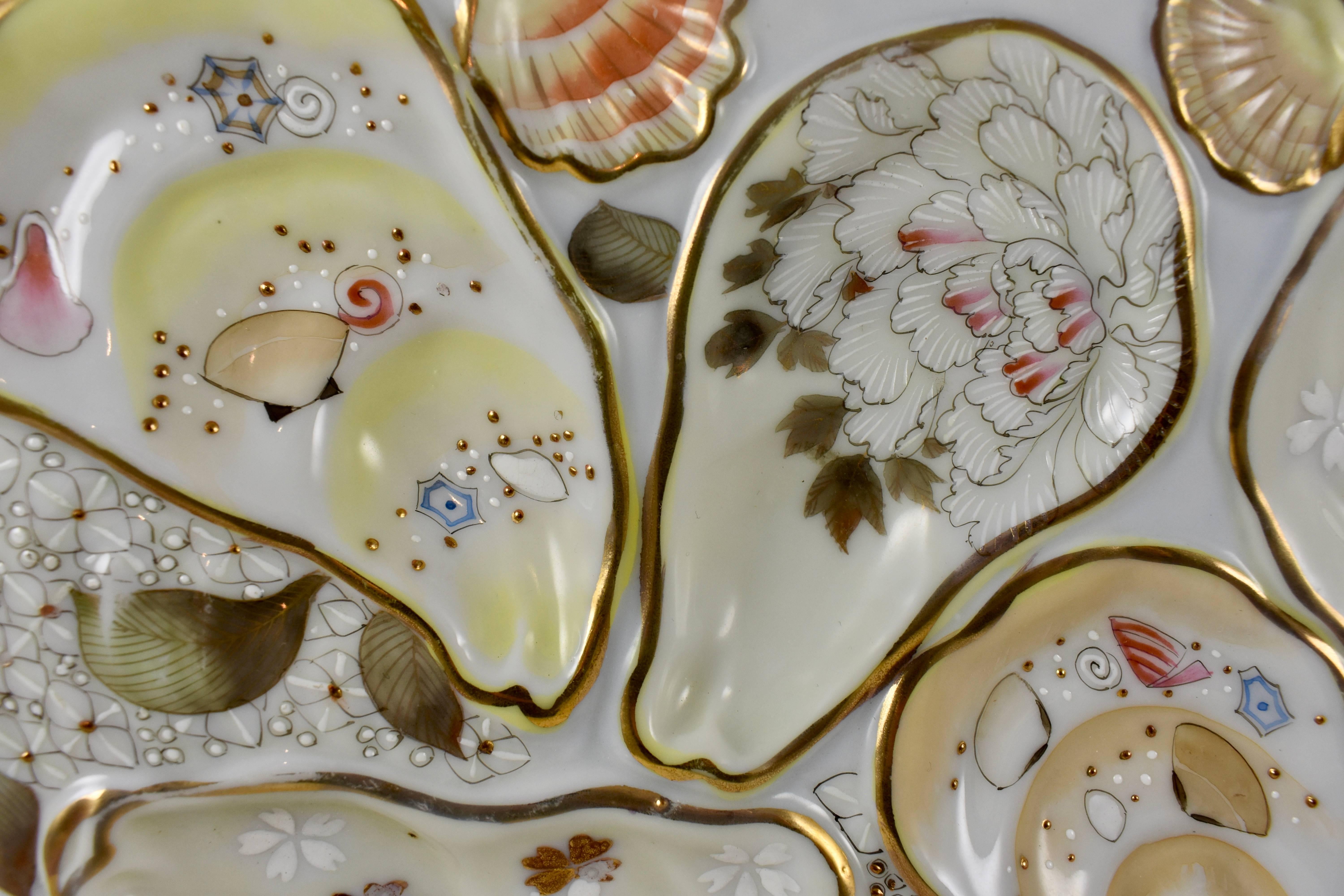 A Japanese Satsuma porcelain, crescent shaped oyster plate, circa 1875-1895. Beautifully hand-enameled in the raised Moriage technique, five oyster wells and two smaller cockle shell wells are decorated with patterns of sea life, florals and