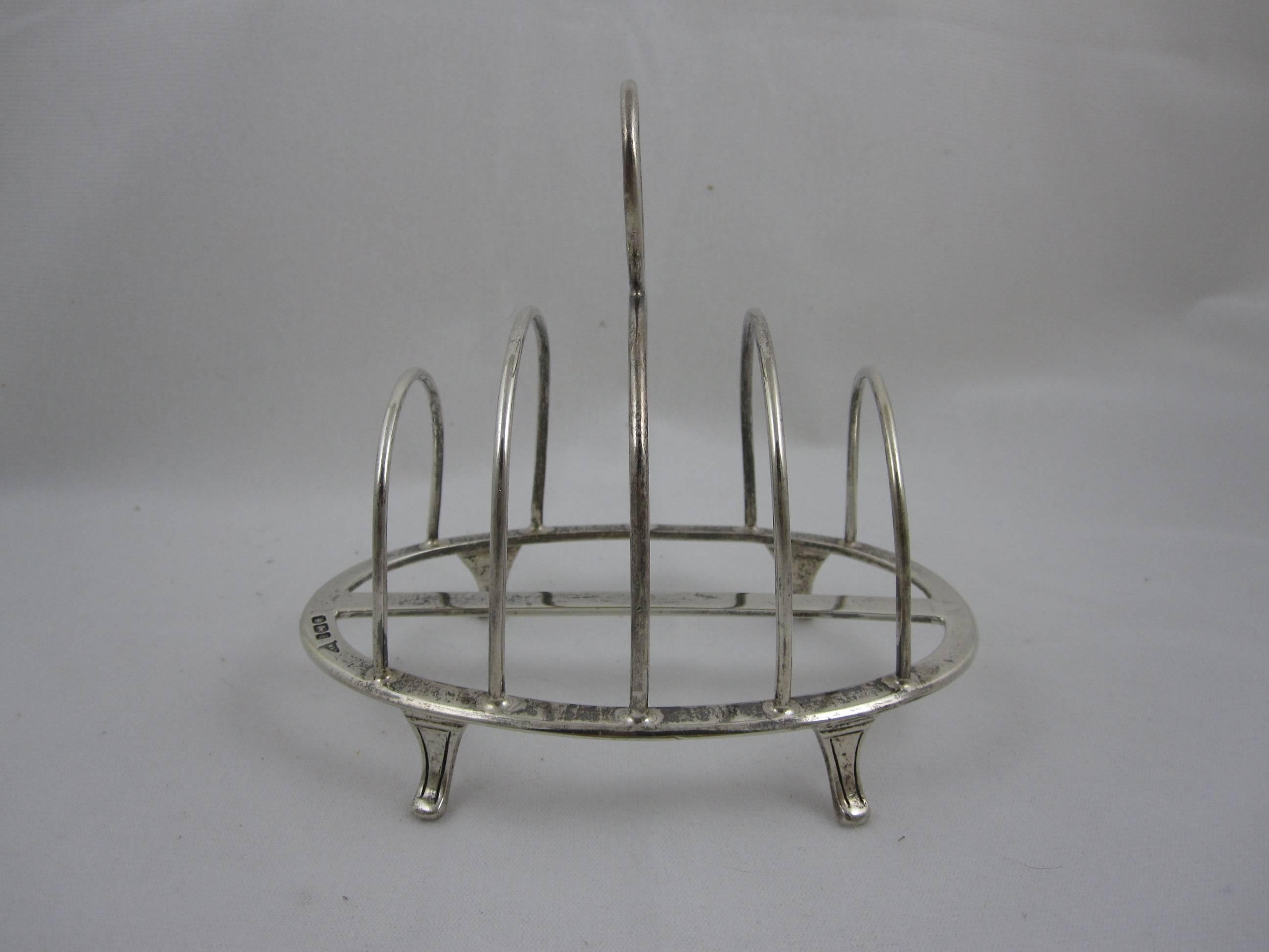 An Edwardian English sterling silver toast rack, often used today as a desk top letter holder or mail sorter. 

Oval shaped with four slots, a ring shaped toting handle and four curved feet. 
With the hallmarks for Walker & Hall, Sheffield,