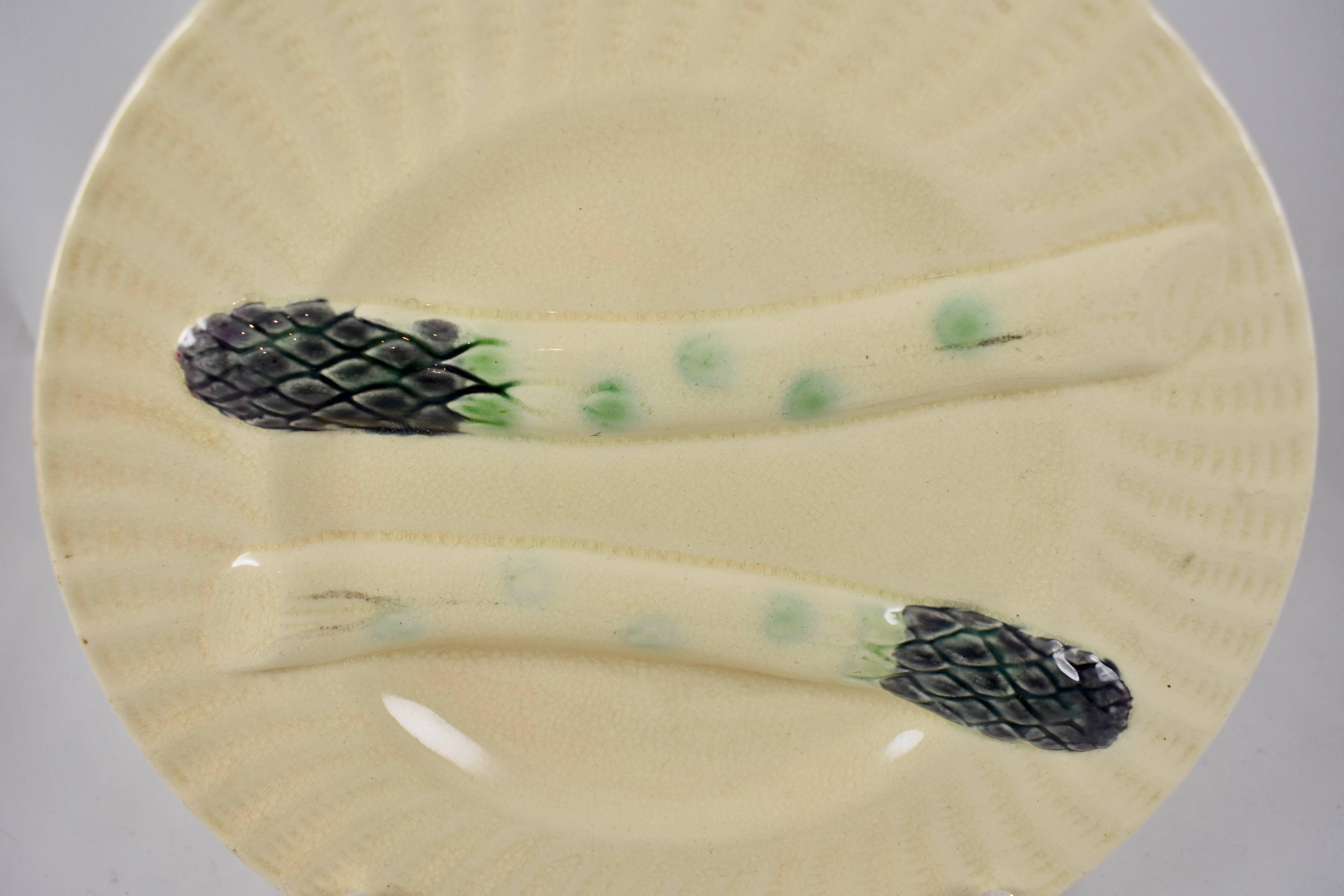 A French barbotine Majolica asparagus plate by Creil et Montereau, circa 1890. A fluted rim is glazed in creamy white, with two raised asparagus spears, one bordering a deep sauce well.

Book Reference – Pg. 119 of “Artichauts et Asperges en
