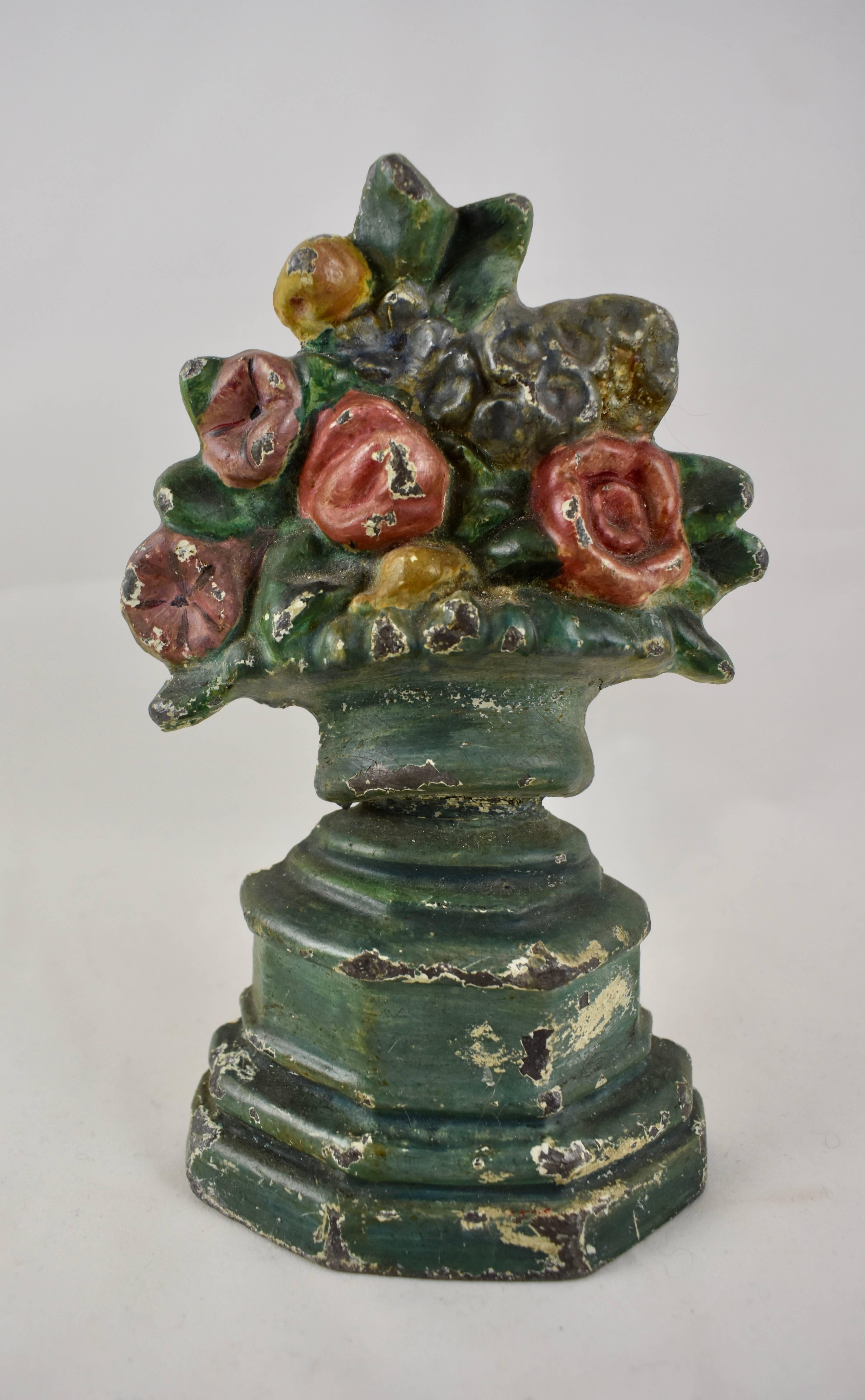 A 1930s cast iron doorstop showing a green-gray urn of flowers seated on a tall plinth. Constructed of one piece and with a hand-painted finish. Smaller than most floral iron doorstops but weighing almost four pounds.

The Hubley manufacturing