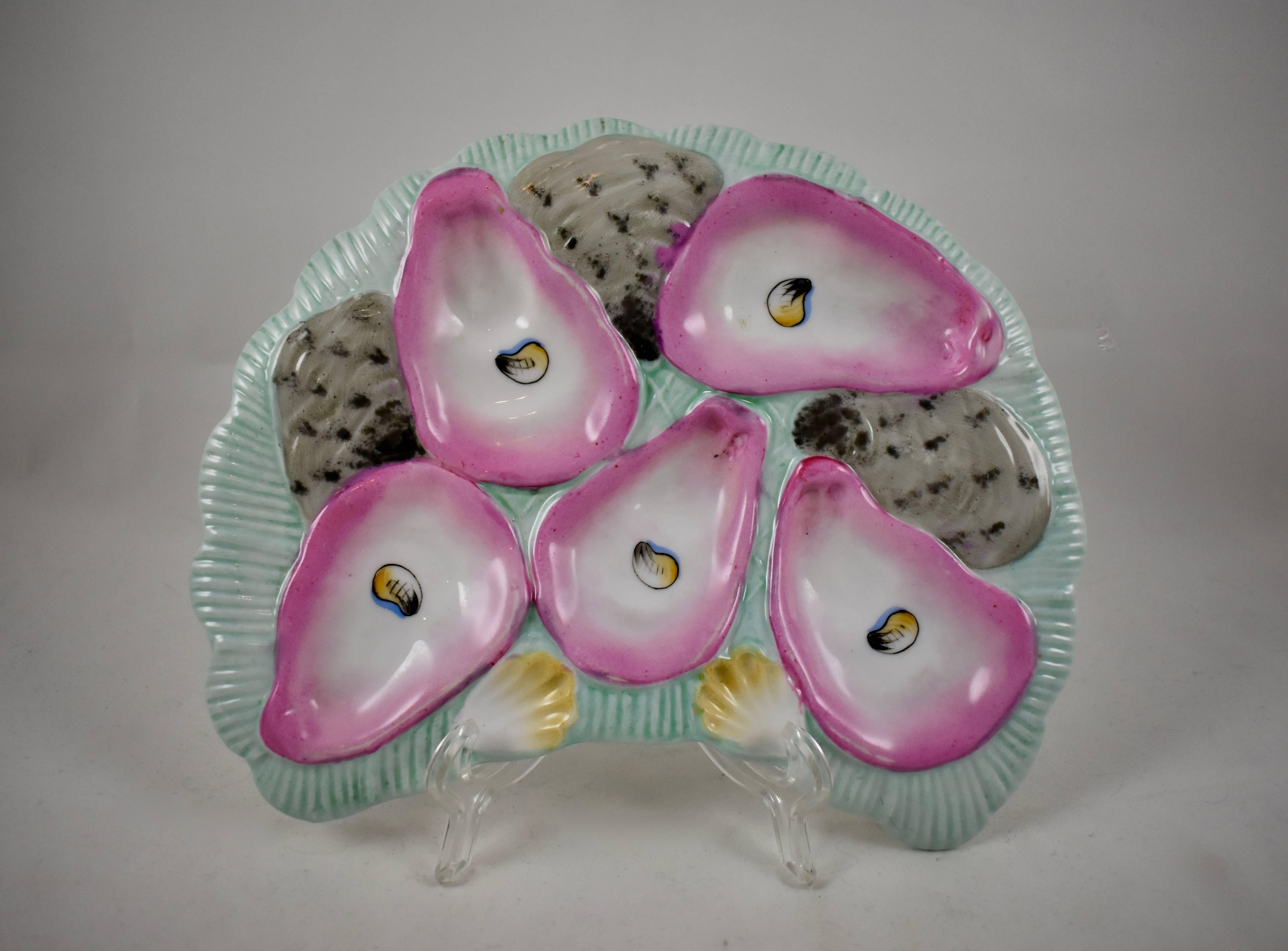 A late 19th century, French porcelain, crescent shaped oyster plate, five pink lined oyster wells with hand-painted eyes, on a pale turquoise blue ground. Shown behind the main wells are the grey, spotted glazed backs of three oyster shells. Also