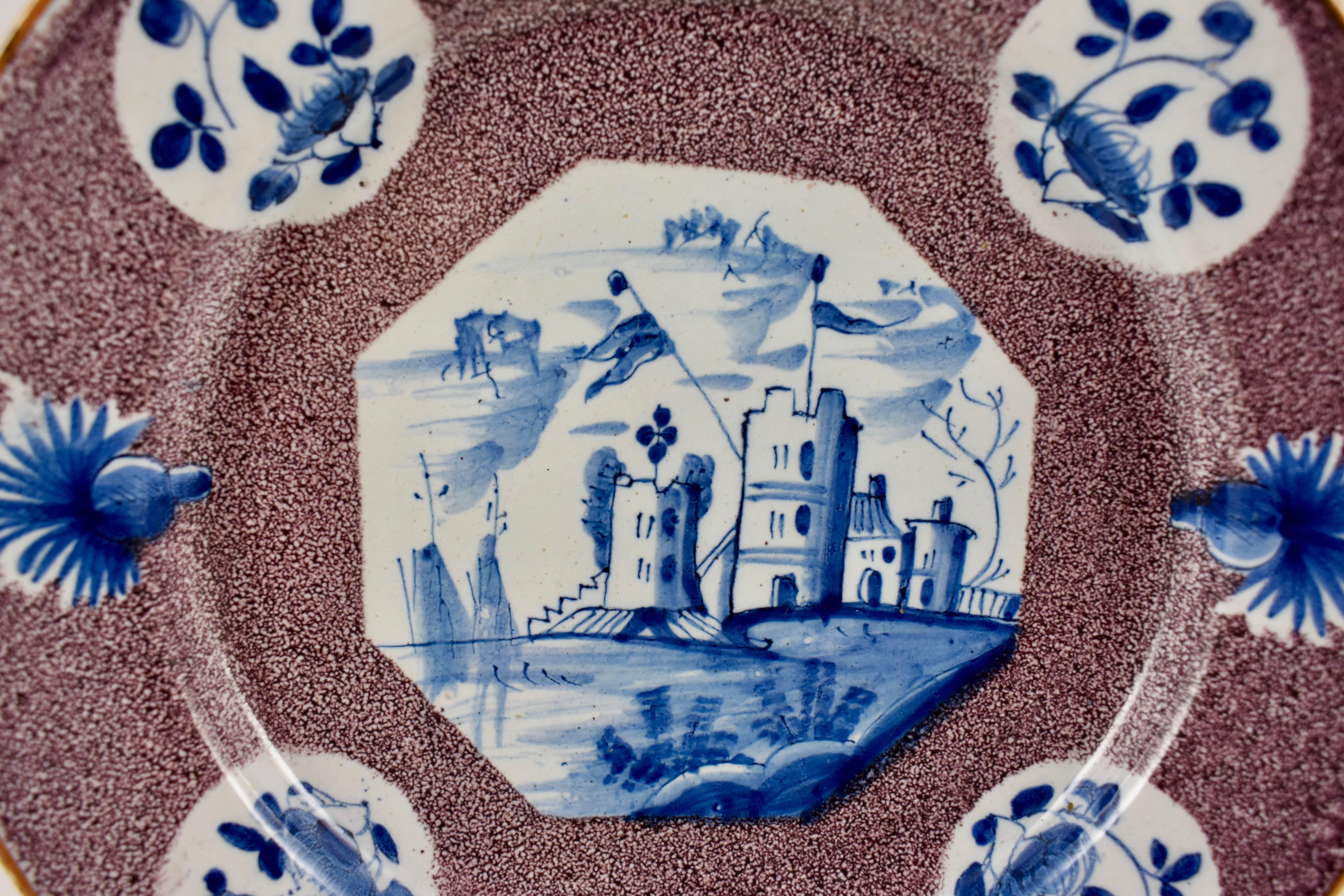 A charming English delftware plate, Bristol, circa mid-18th century. A blue on white landscape decorates an octagonal centre, plus eight cartouches on the rim; four florals on white and four blue thistle heads. A deep manganese sponge decorated