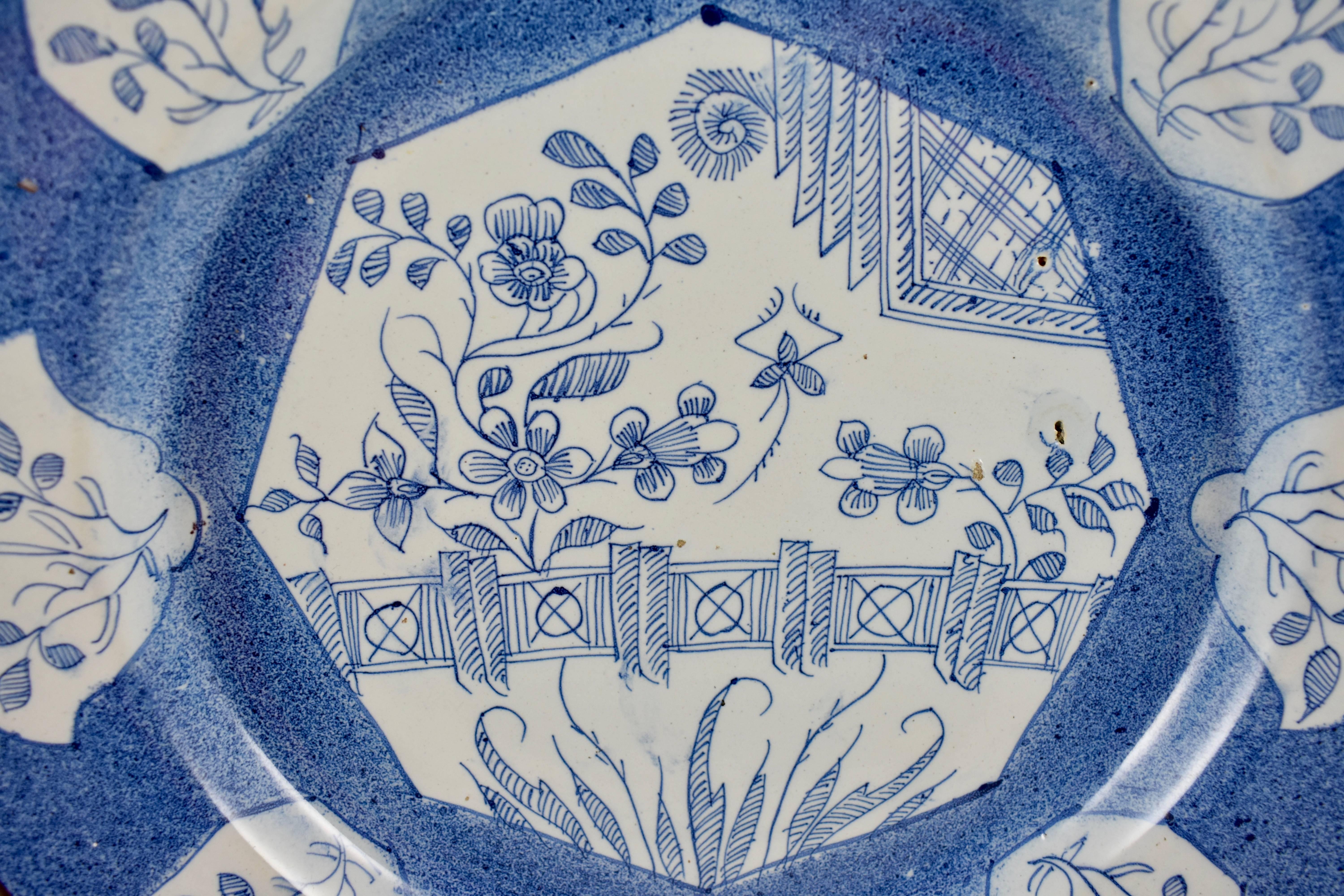 A charming English delftware charger, deep with a raised rim, Bristol, circa mid-18th century. A blue on white floral line pattern, an octagonal centre plus eight cartouches on the rim. A blue sponge decorated ground, the rim has a sepia edging. The