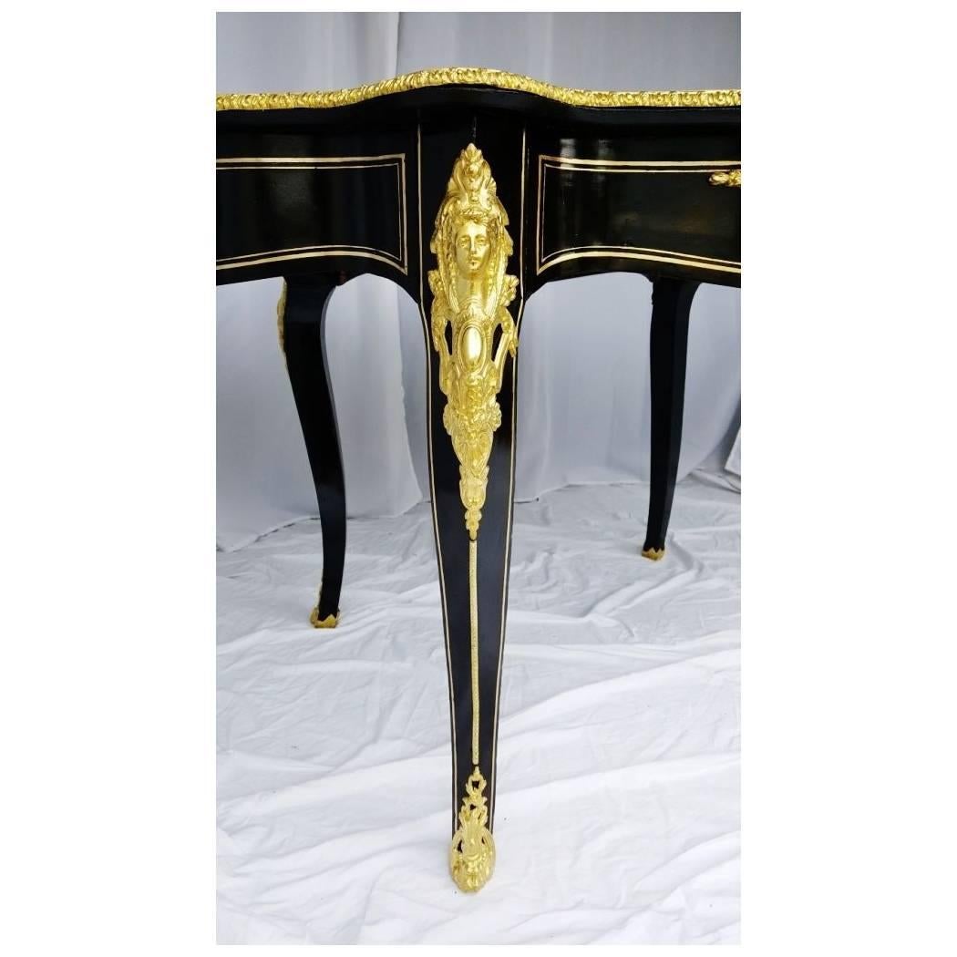 Table Louis XV with inlays boulle and large brass ornaments. Mold, ornamental bronze caryatids on the legs, clogs, bronze lion head on the belt. Plateau patterned foliage, scrolls and interlacing, with a large central cartridge tortoise shell