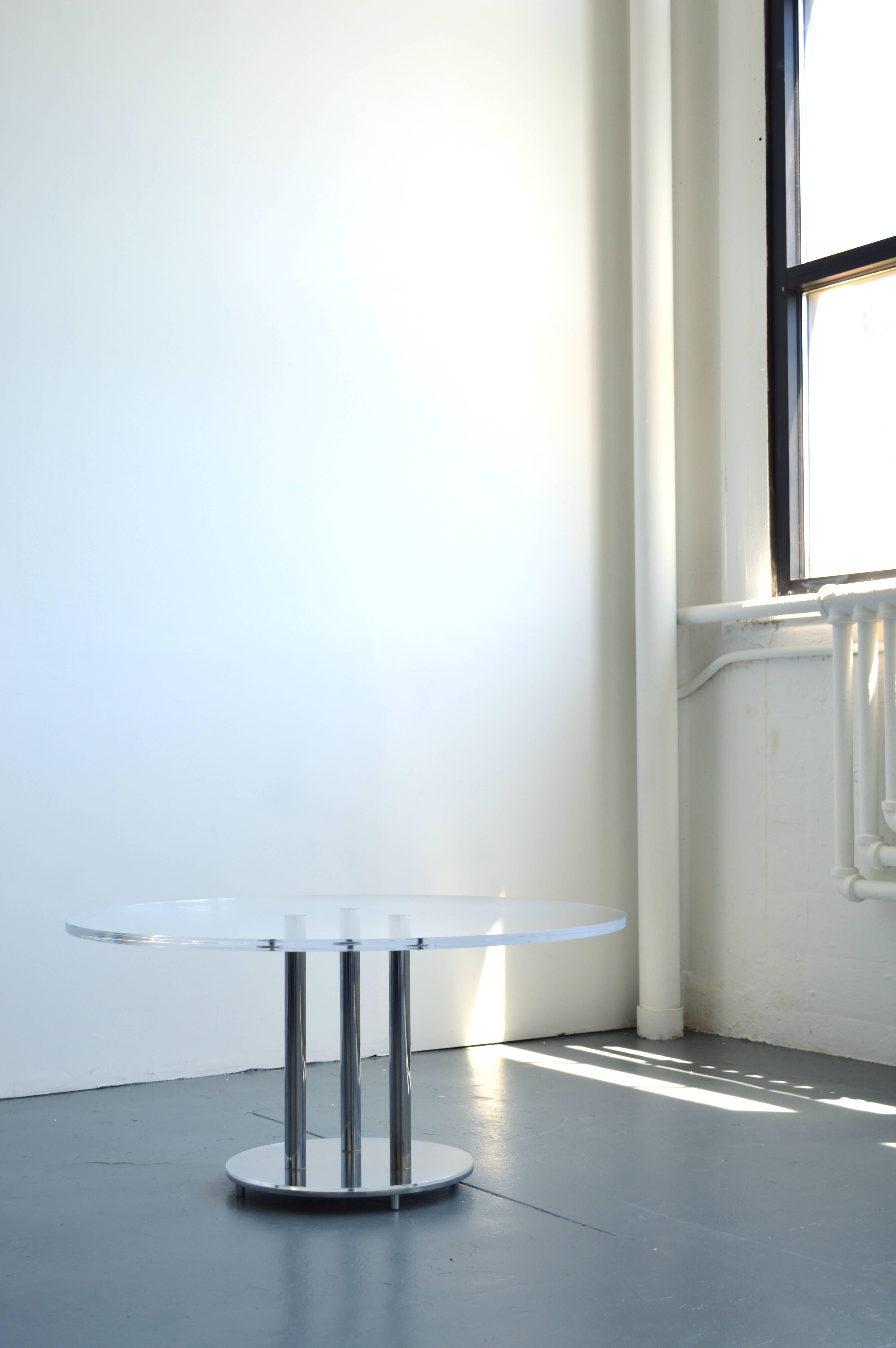 This Charles Hollis Jones designed coffee table has a Lucite top sitting atop three chrome legs and a circular chrome base. Table base is 16